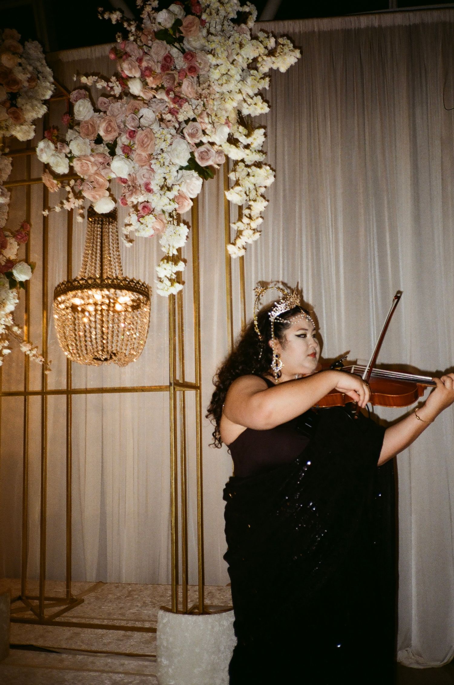A violinist in traditional headwear plays Bollywood tunes on a floral-lit valima reception stage at the adler Planetarium chicago
