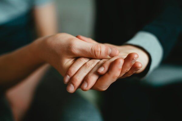 Two hands tenderly clasped together in an intimate, close-up shot.