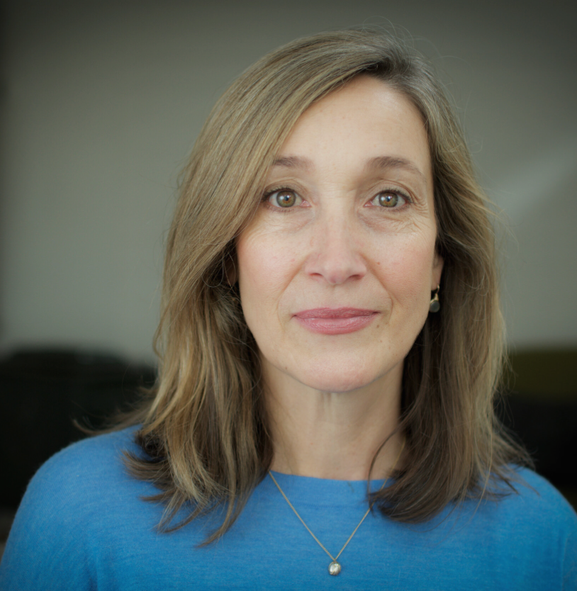 Professional headshot of a therapist wearing a blue sweater against a dark background.