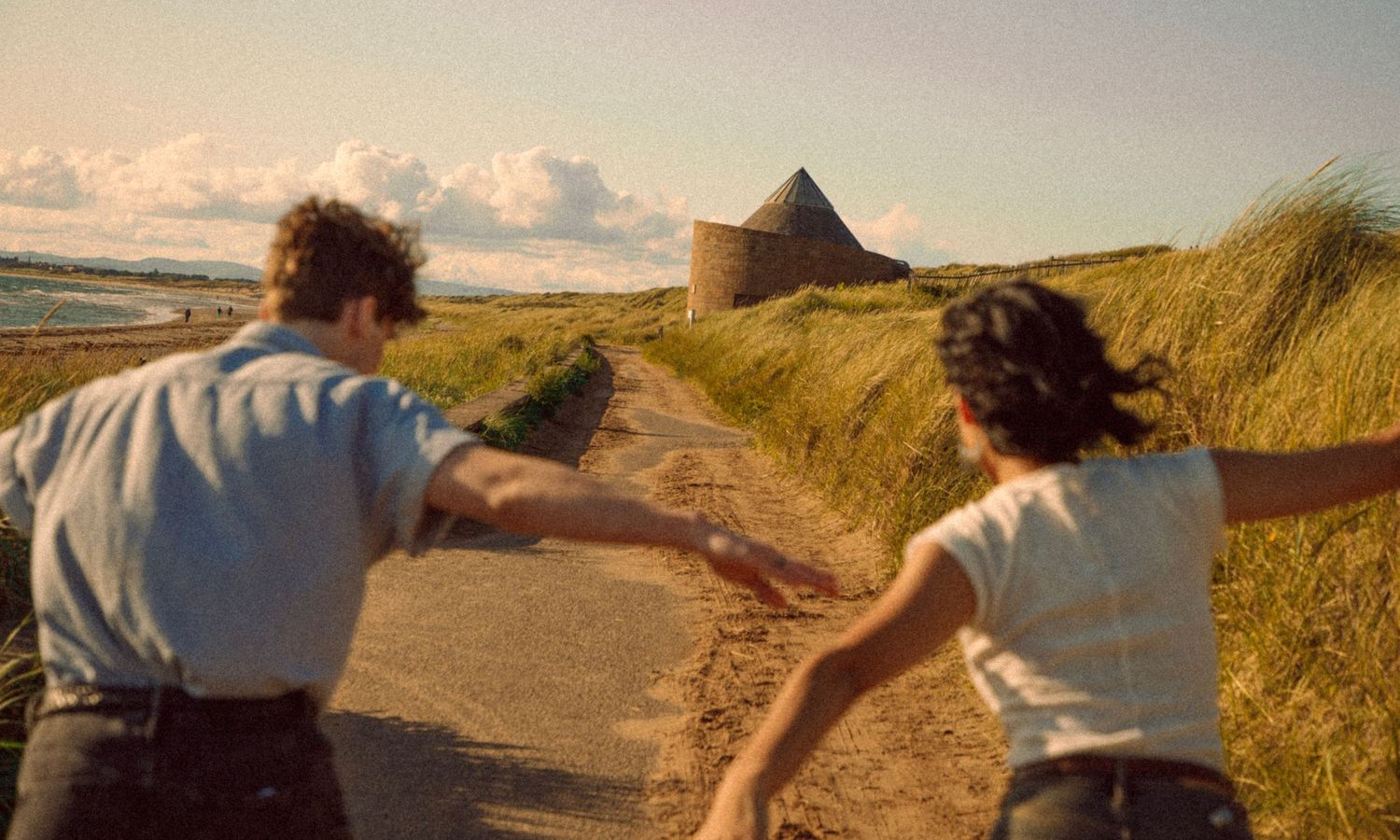young-couple-running-through-the-countryside-in-scotland-during-a-cinematic-photoshoot