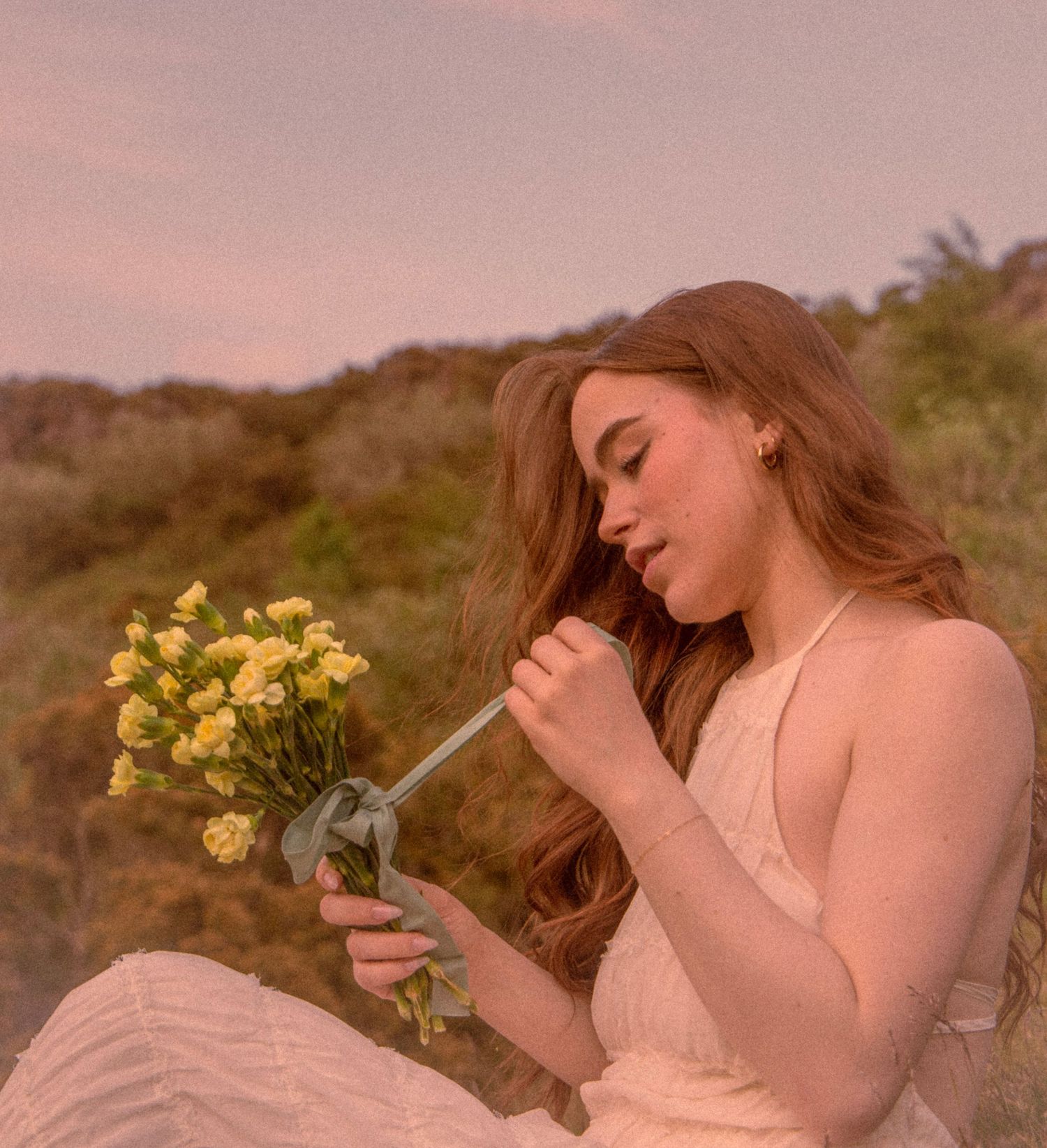 bride-tying-a-ribbon-around-her-bouquet-whilst-sitting-on-a-mountain-in-the-scottish-highlands