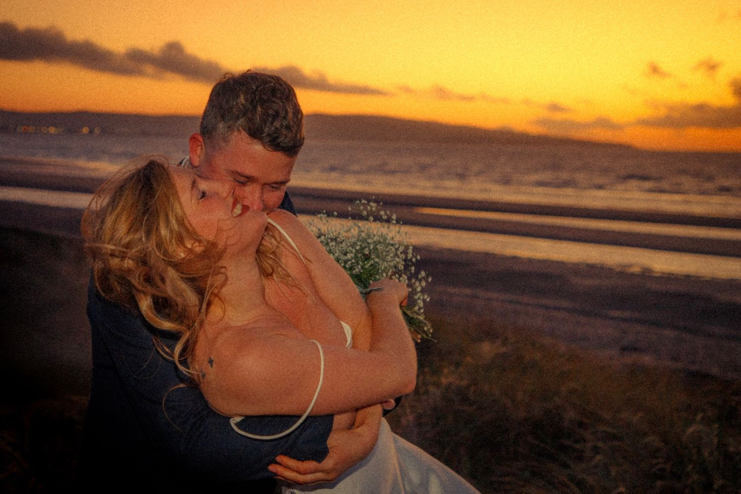 couple-embracing-happily-during-sunset-beach-elopement