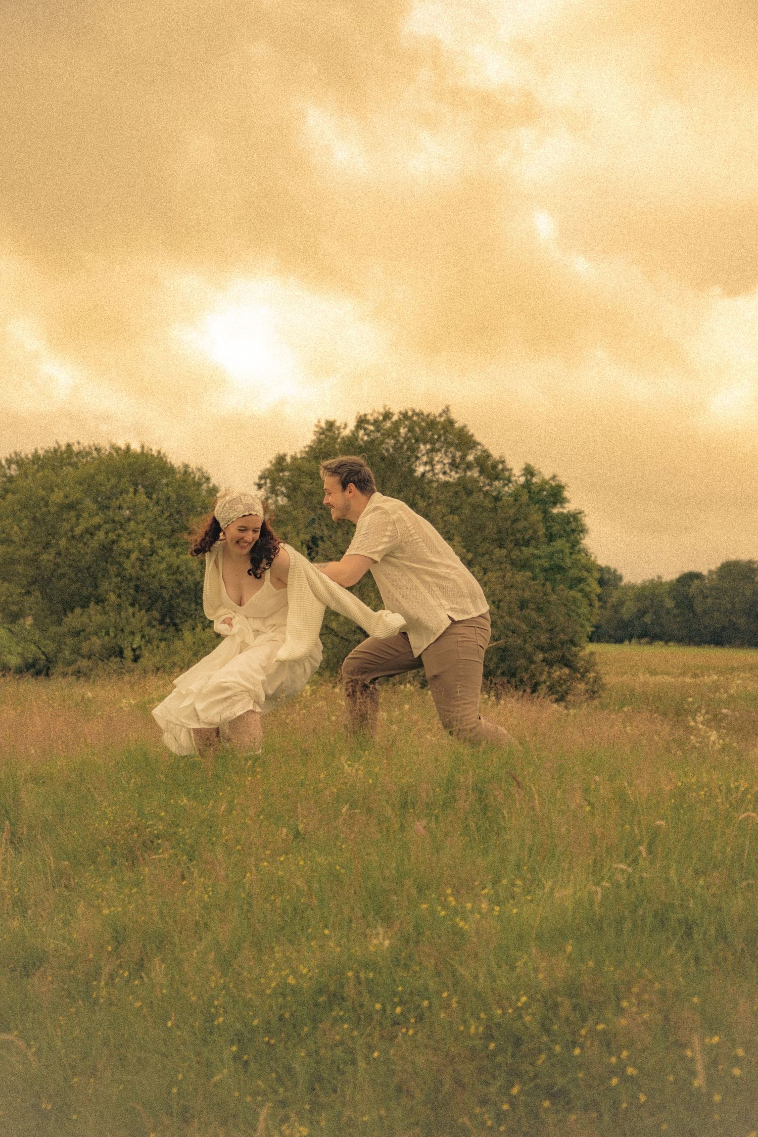 couple-chasing-each-other-around-during-a-cinematic-cottagecore-style-engagement-photoshoot-in-the-Scottish-countryside