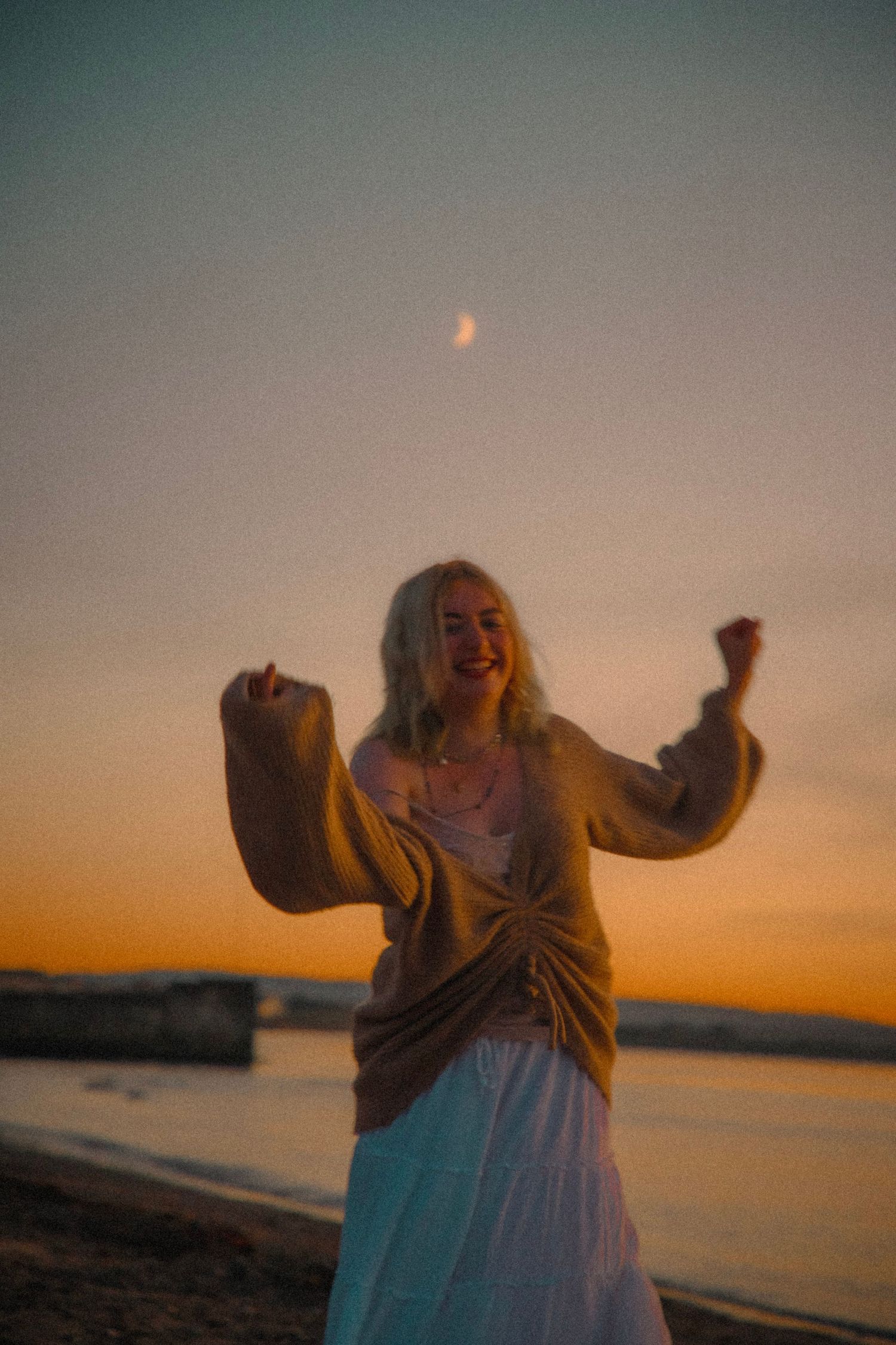 girl-smiling-and-playing-on-a-beach-during-sunset-and-blue-hour