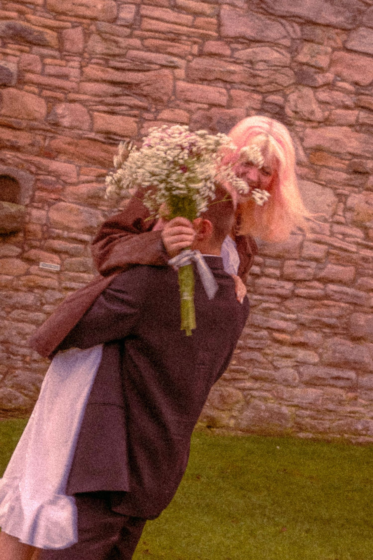 young-couple-embracing-happily-outside-a-scottish-castle-with-a-bouquet-of-flowers