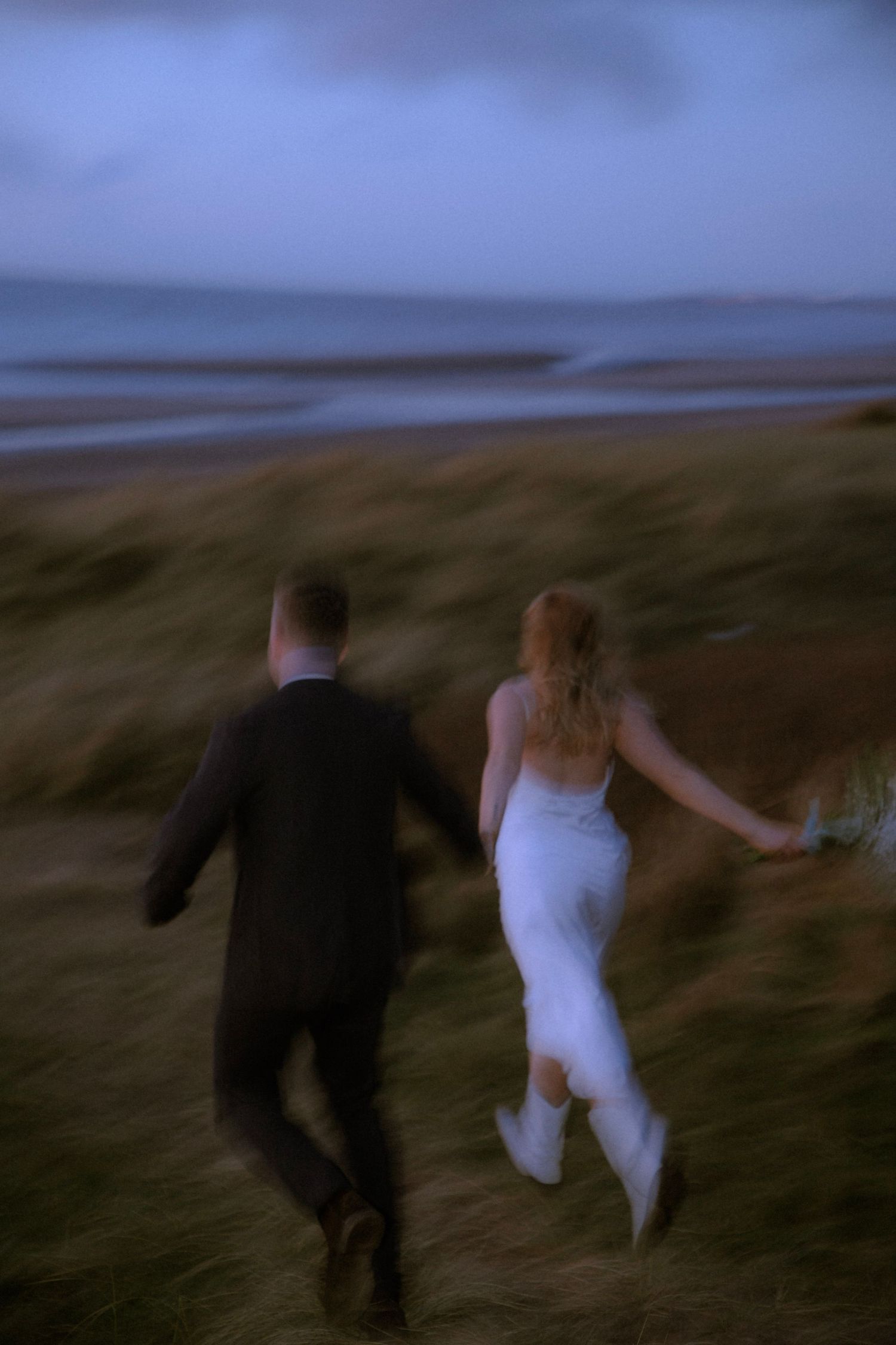 newlywed-couple-running-down-beach-at-blue-hour