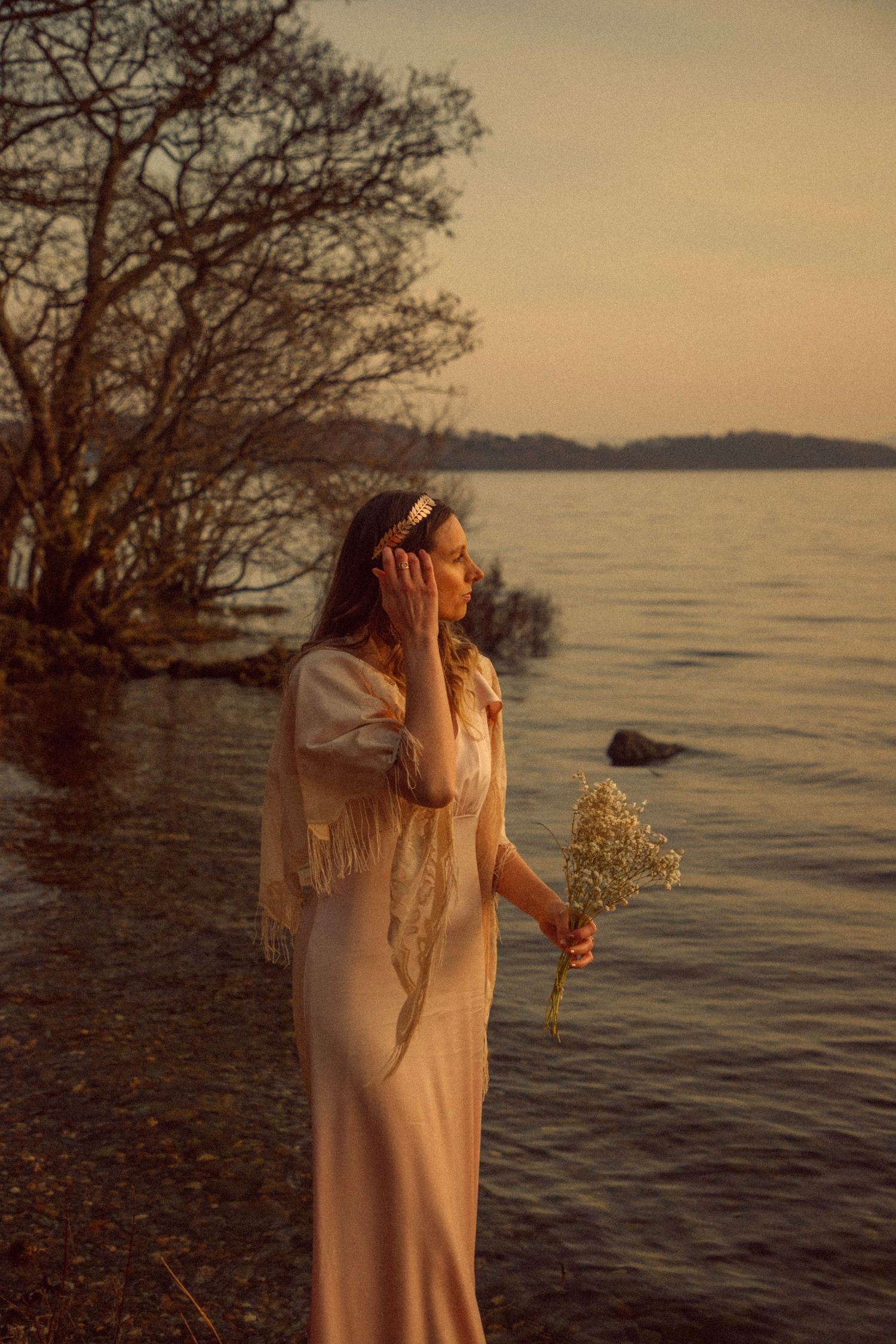 girl-walking-along-the-shore-on-loch-lomond-in-a-vintage-style-silk-wedding-dress-with-flowers