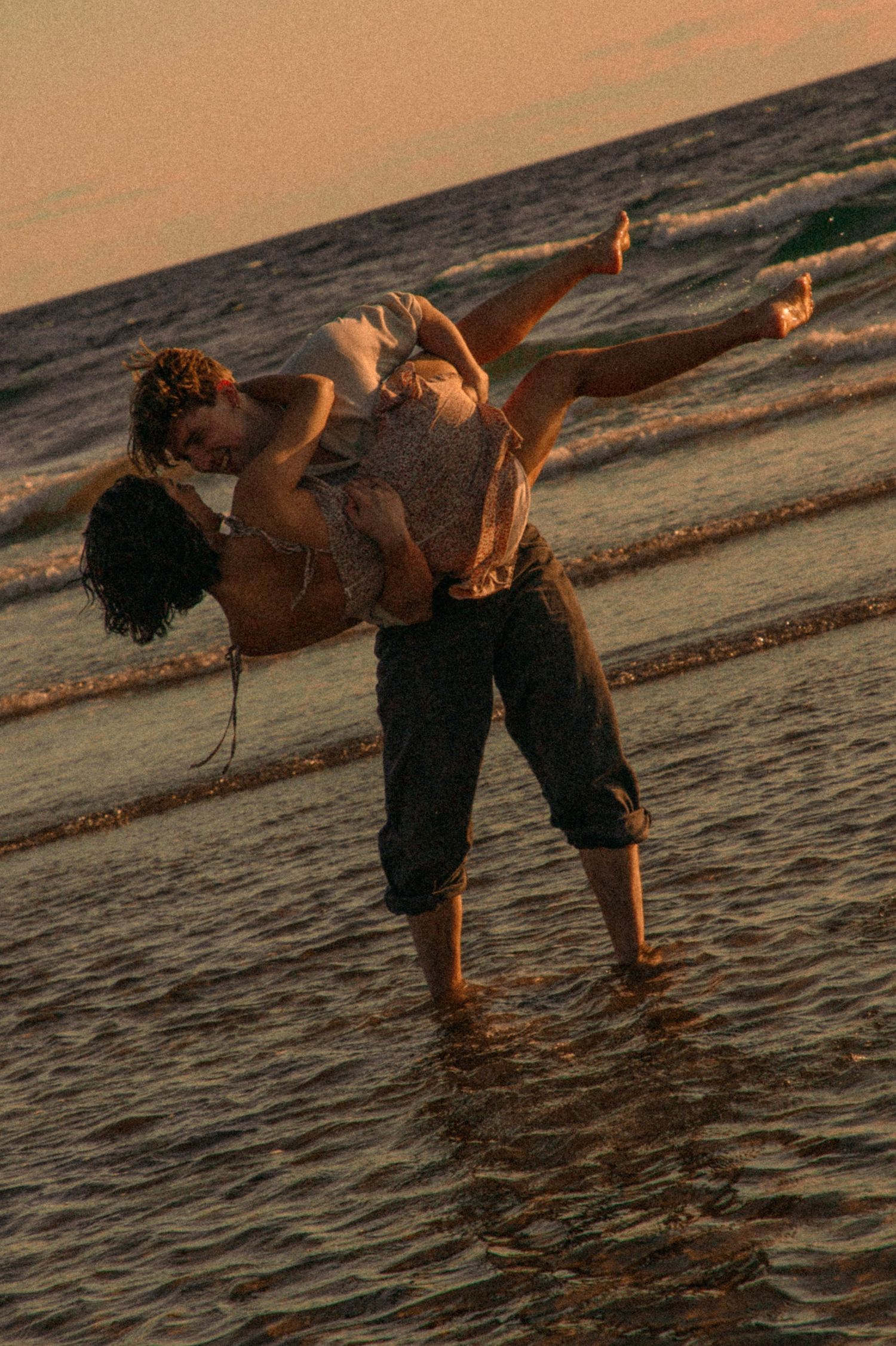 young-couple-playing-together-in-the-water-during-a-cinematic-beach-photoshoot