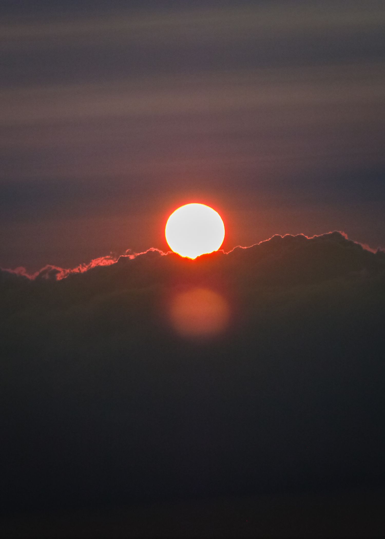 Dramatic sunset sequence showing sun descending behind dark clouds.