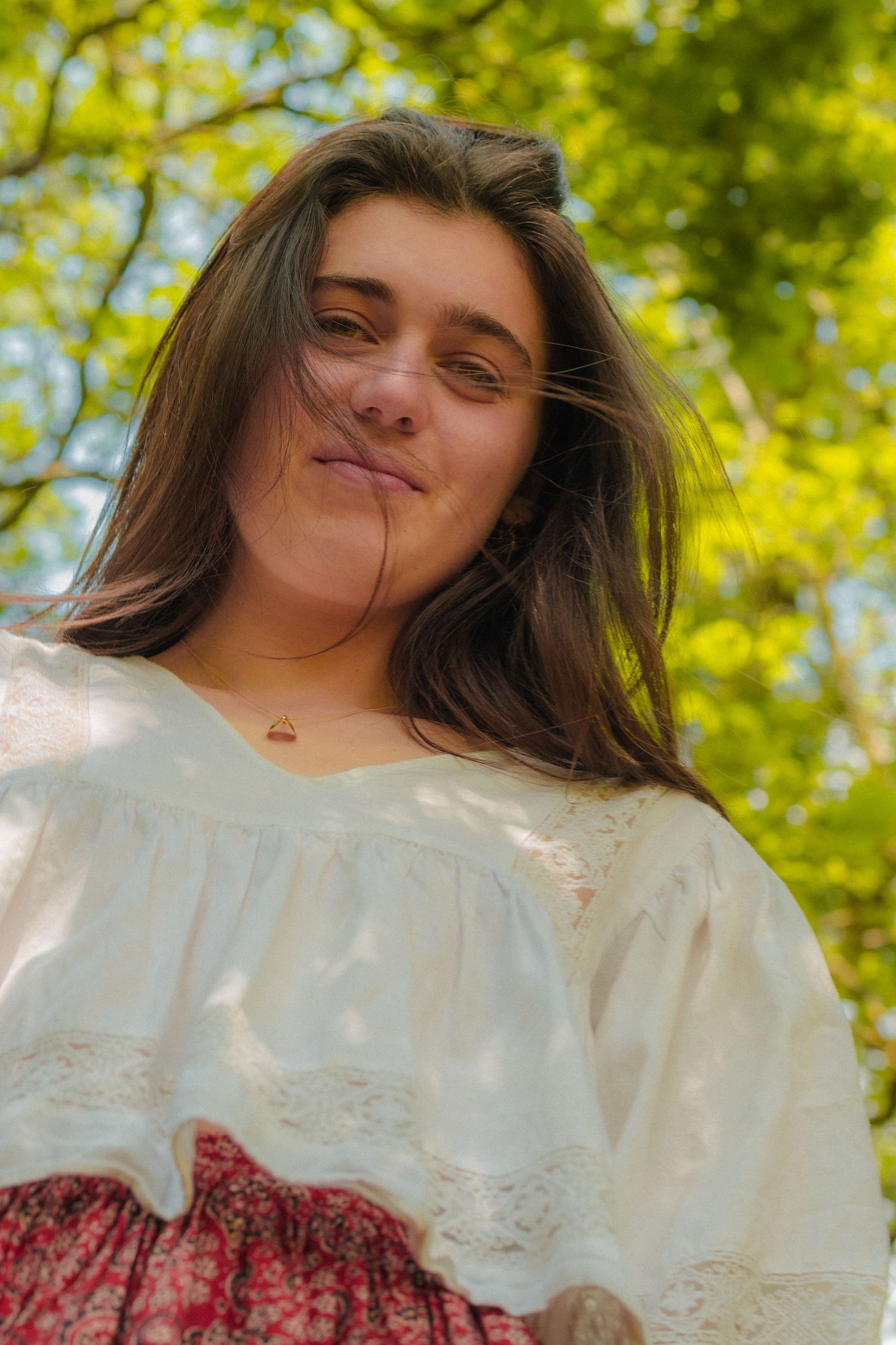 Vintage-style portrait against vibrant green leaves features white lace blouse details.