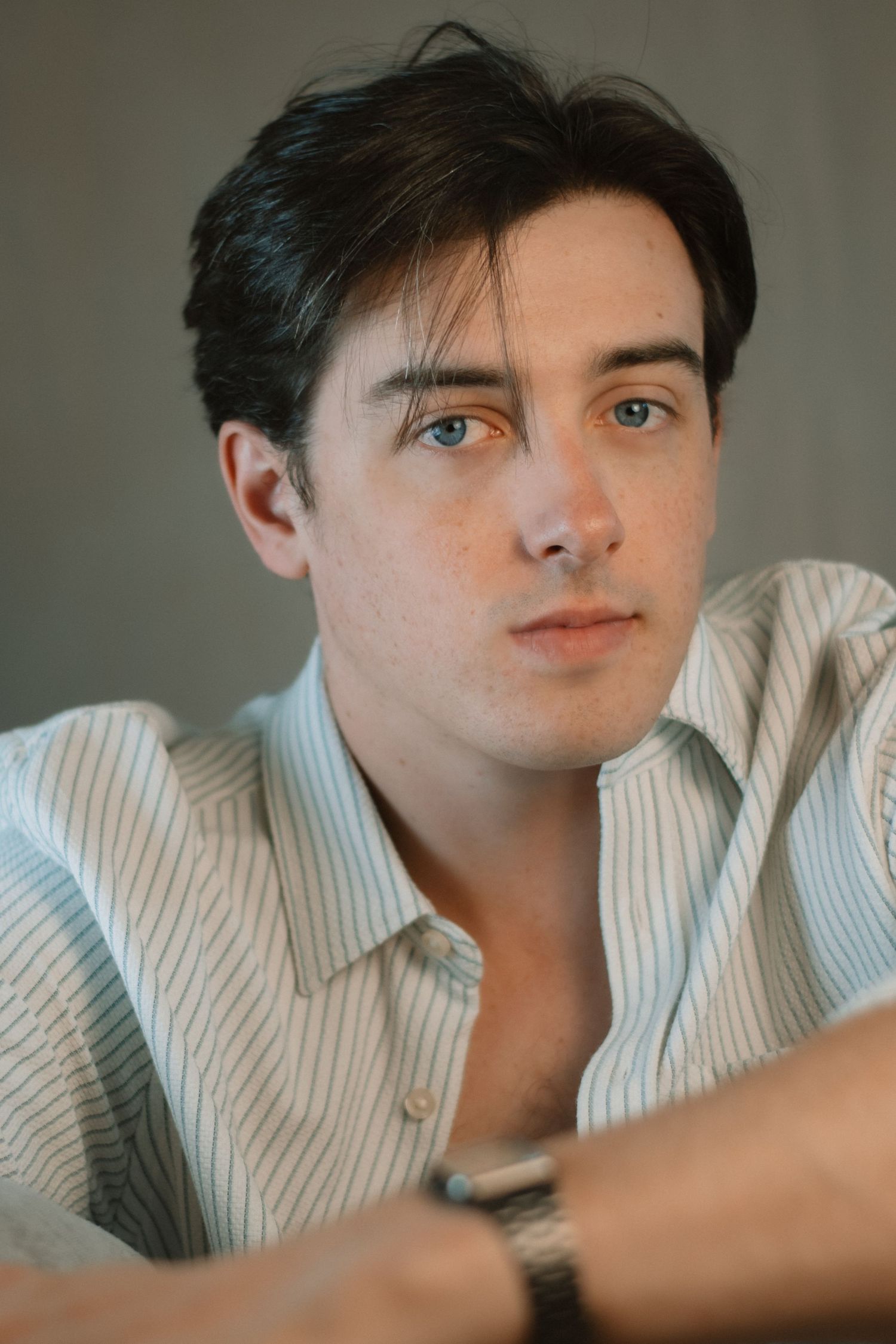 Casual portrait series with soft lighting and striped shirt against neutral backdrop.