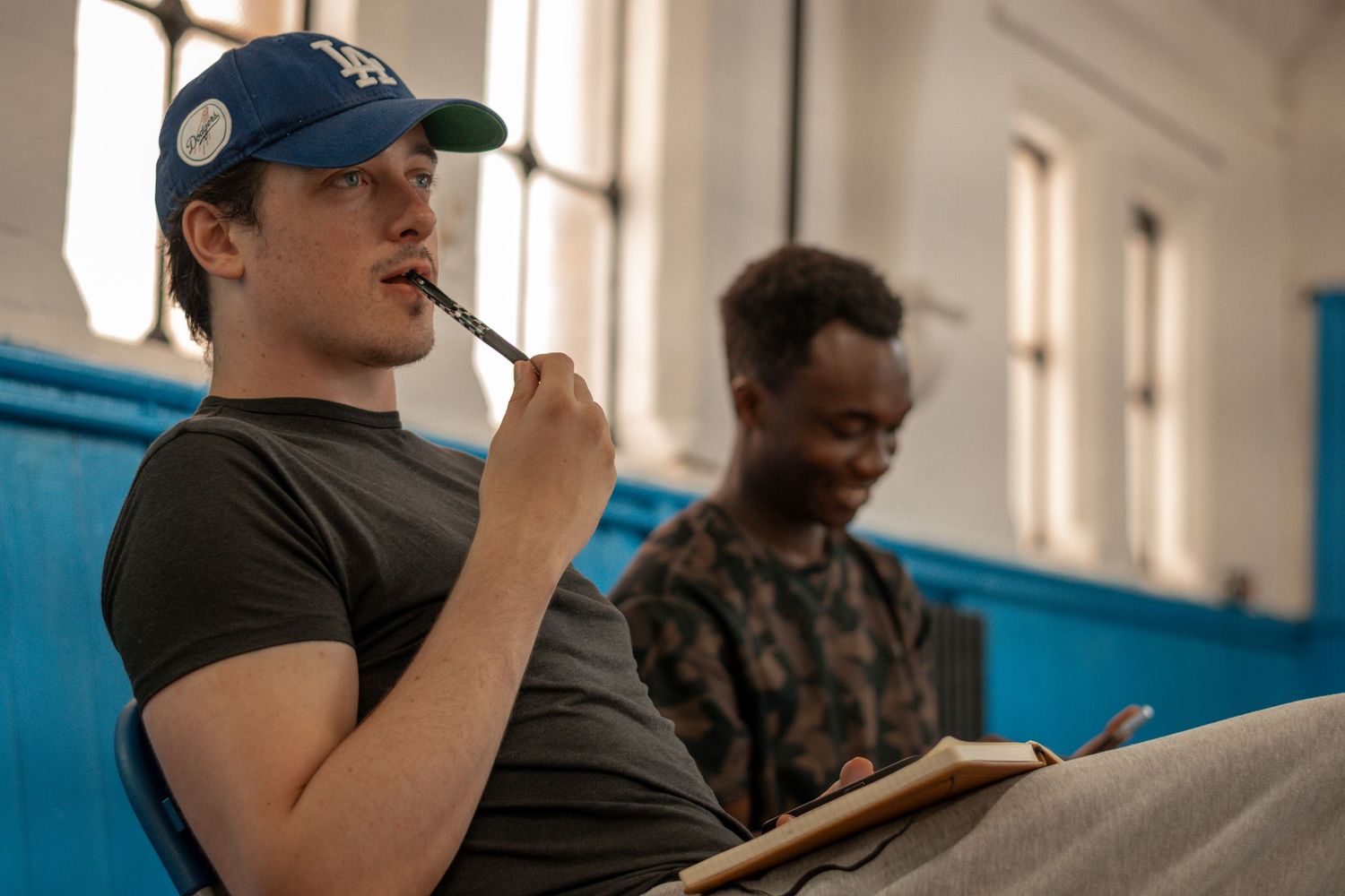 Students taking notes during a classroom lecture in an institutional setting.