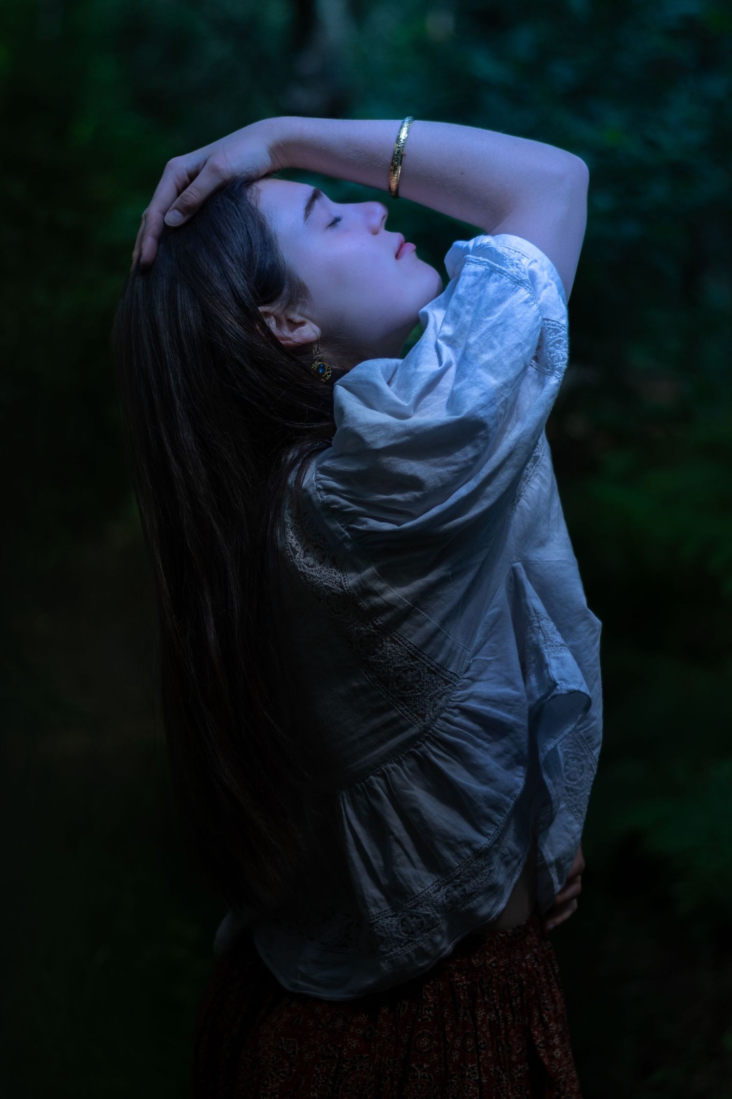 Artistic portrait in dim lighting with figure in flowing white blouse.