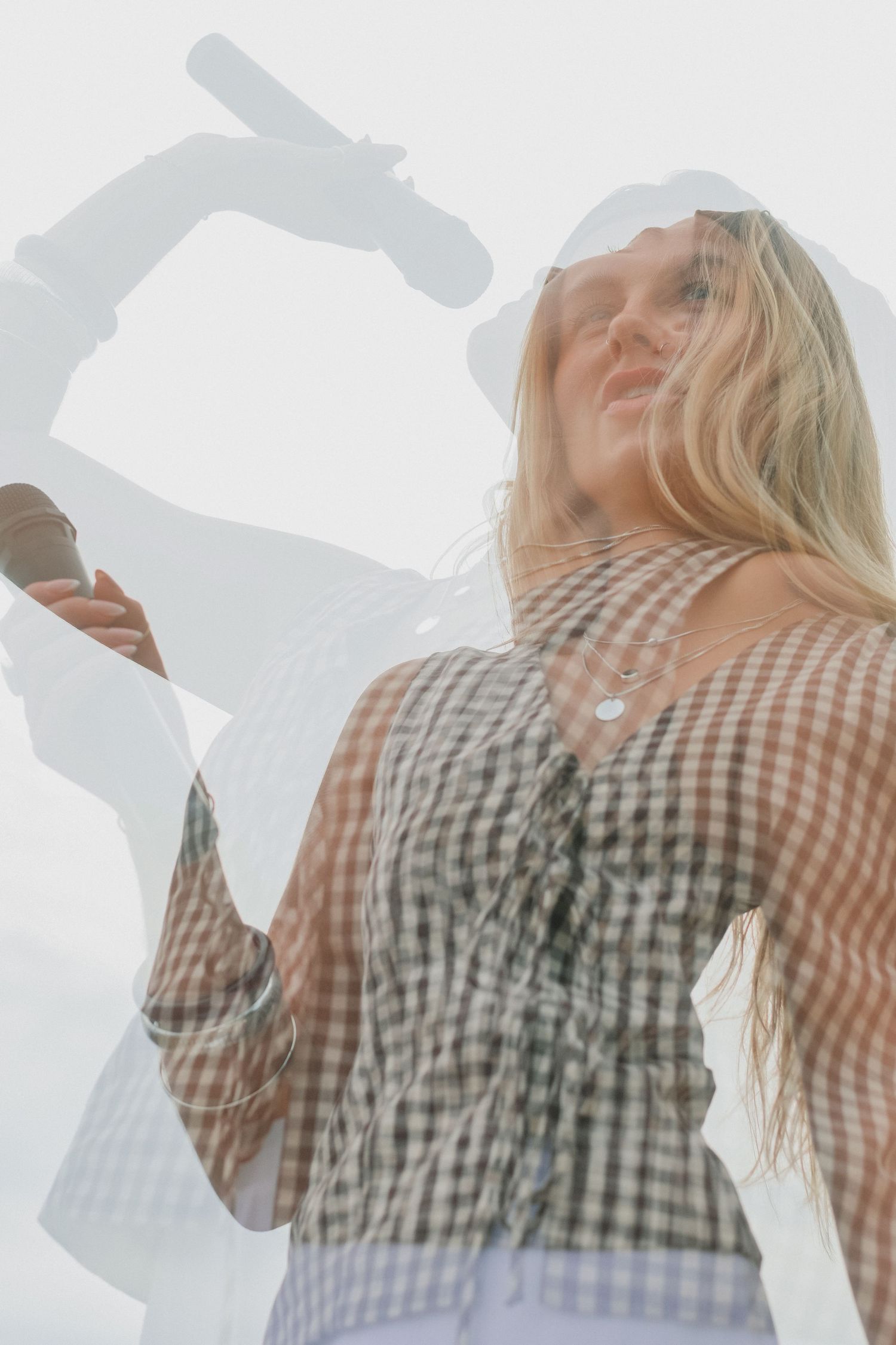 Multiple exposure of person drinking against bright overexposed background.