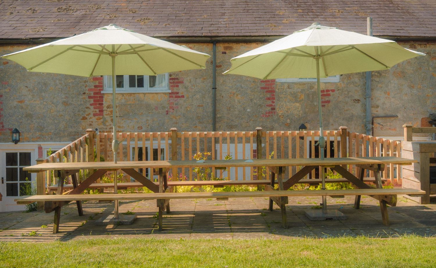 Stone building exterior with wooden patio umbrellas and rustic fencing.