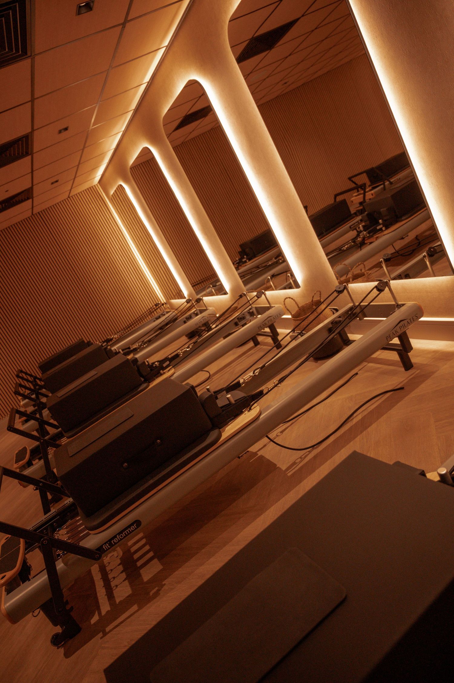 Pilates reformer studio with warm amber lighting and elegant arched wall details creating a luxurious workout space.