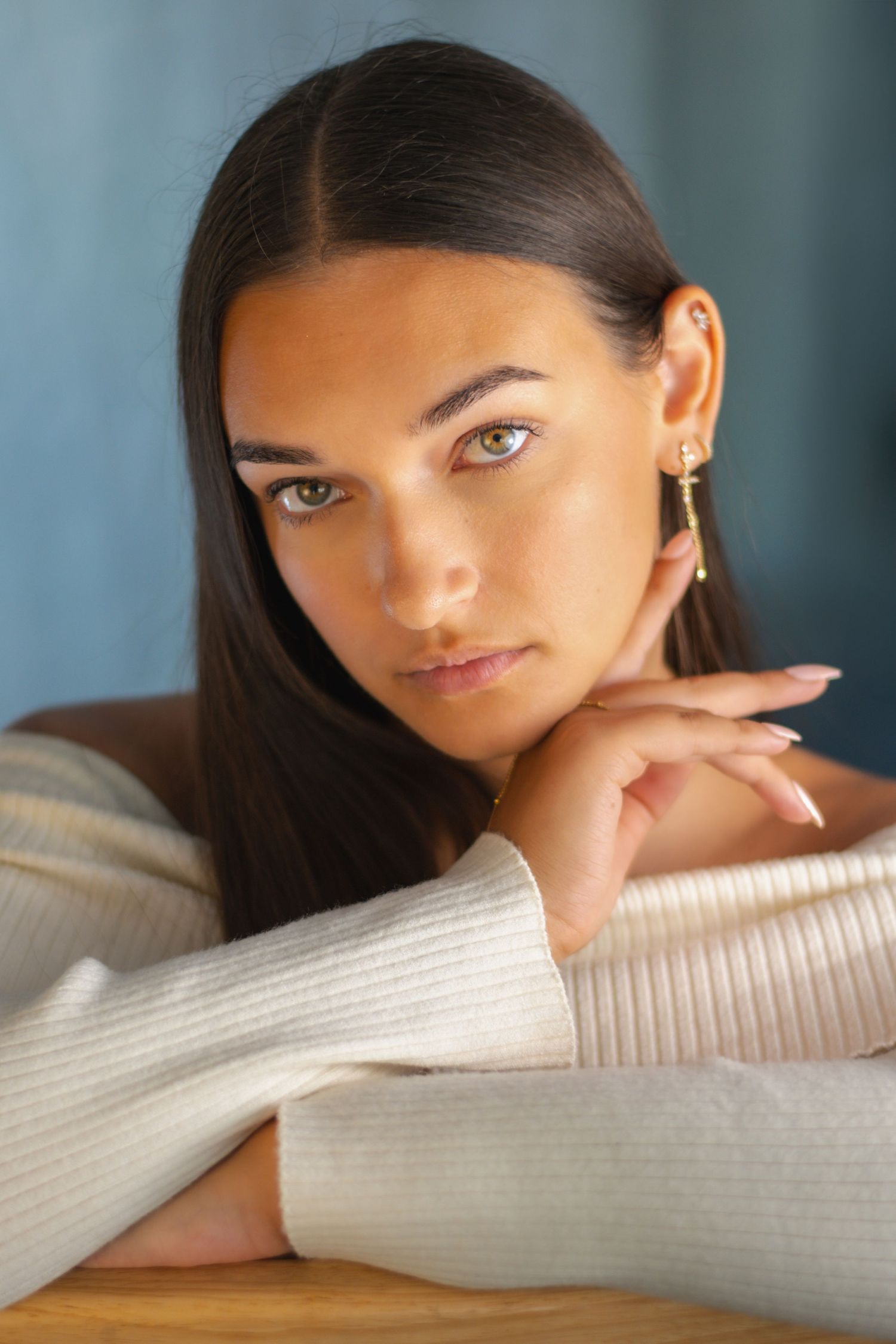 A series of artistic portrait shots against a blue background with a white sweater.
