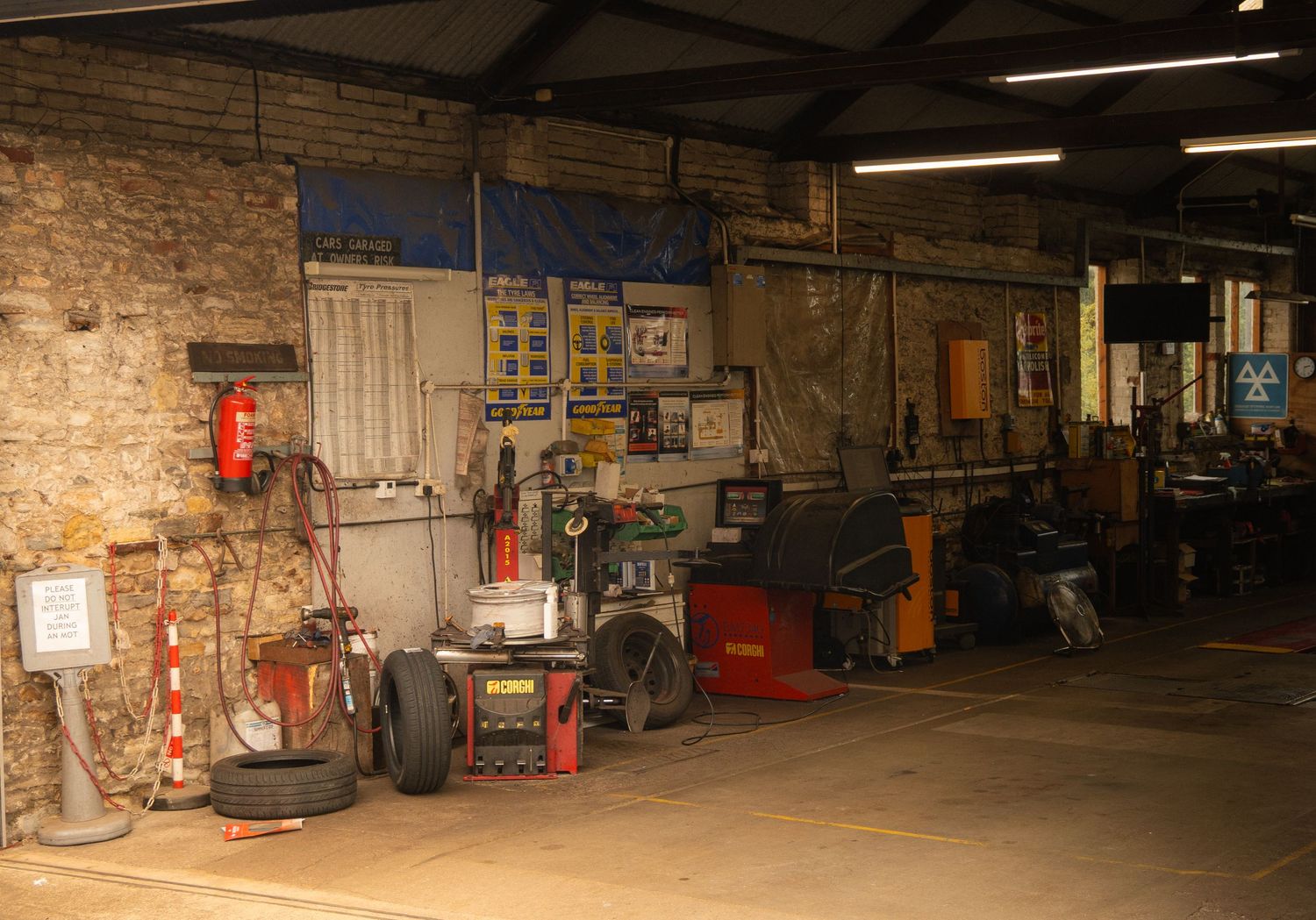 Interior of a dimly lit industrial warehouse with brick walls and equipment.