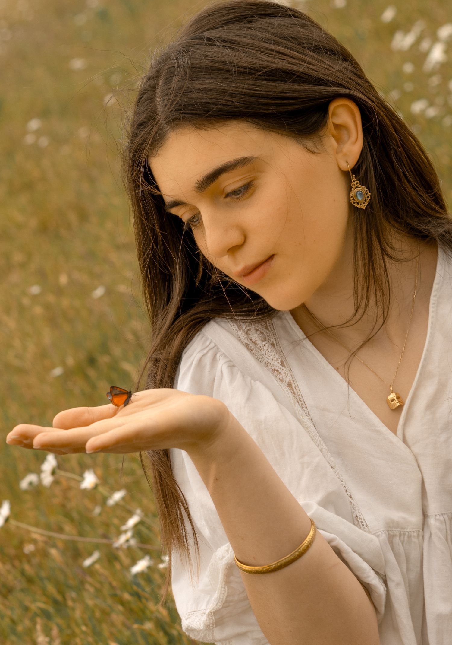 A graceful hand gesture captured in golden sunlight with delicate jewelry.