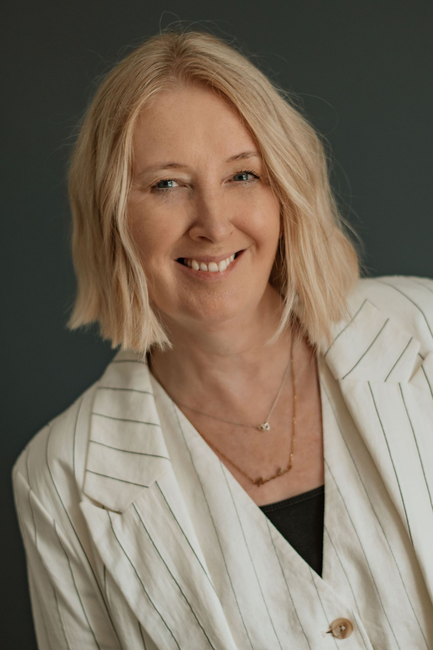 Professional headshots featuring warm smile and white pinstriped blazer.