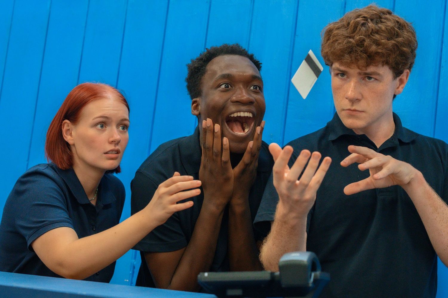 Group of people engaged in animated conversation against blue backdrop.