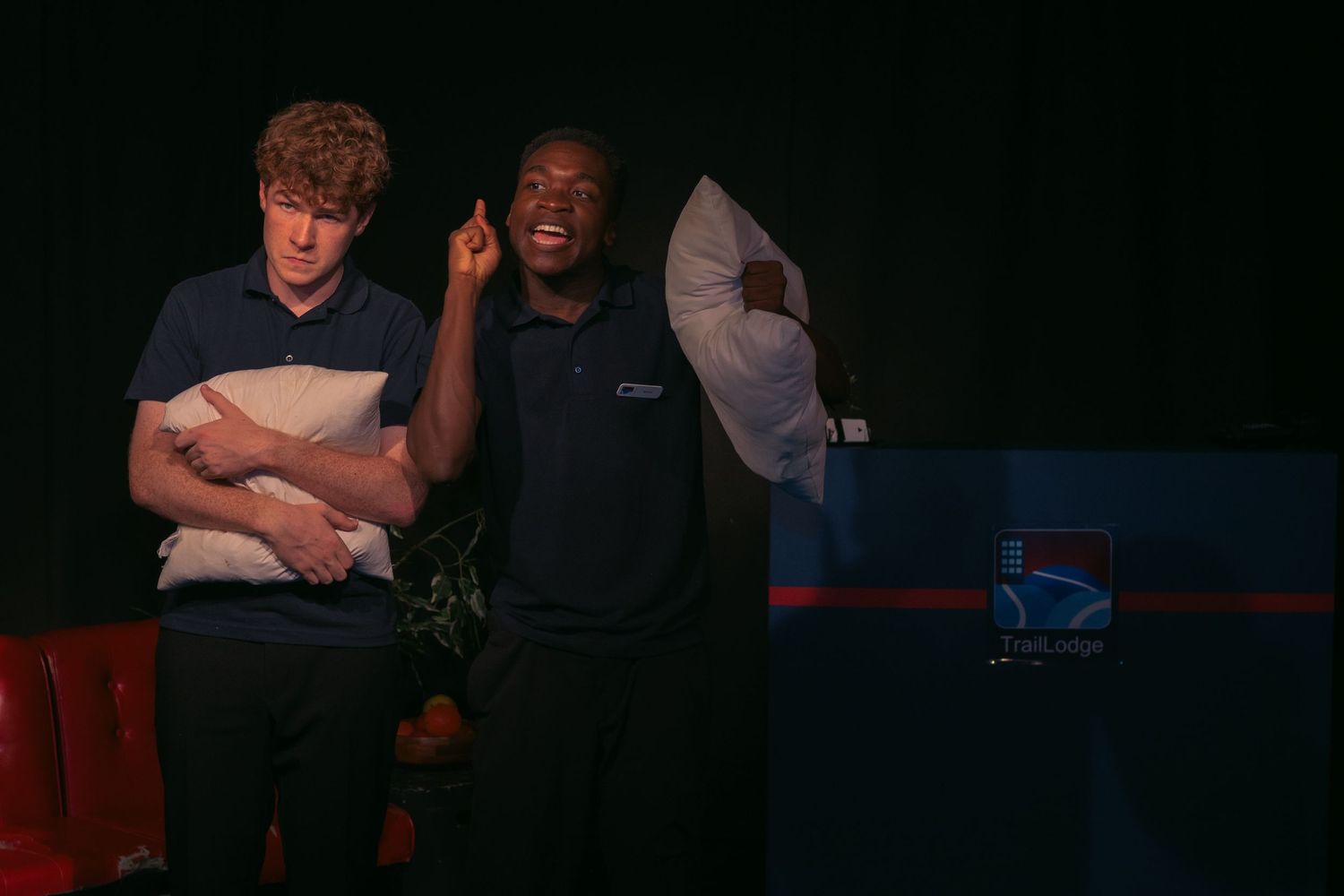 Two people wearing navy uniforms stand together in a dark environment.