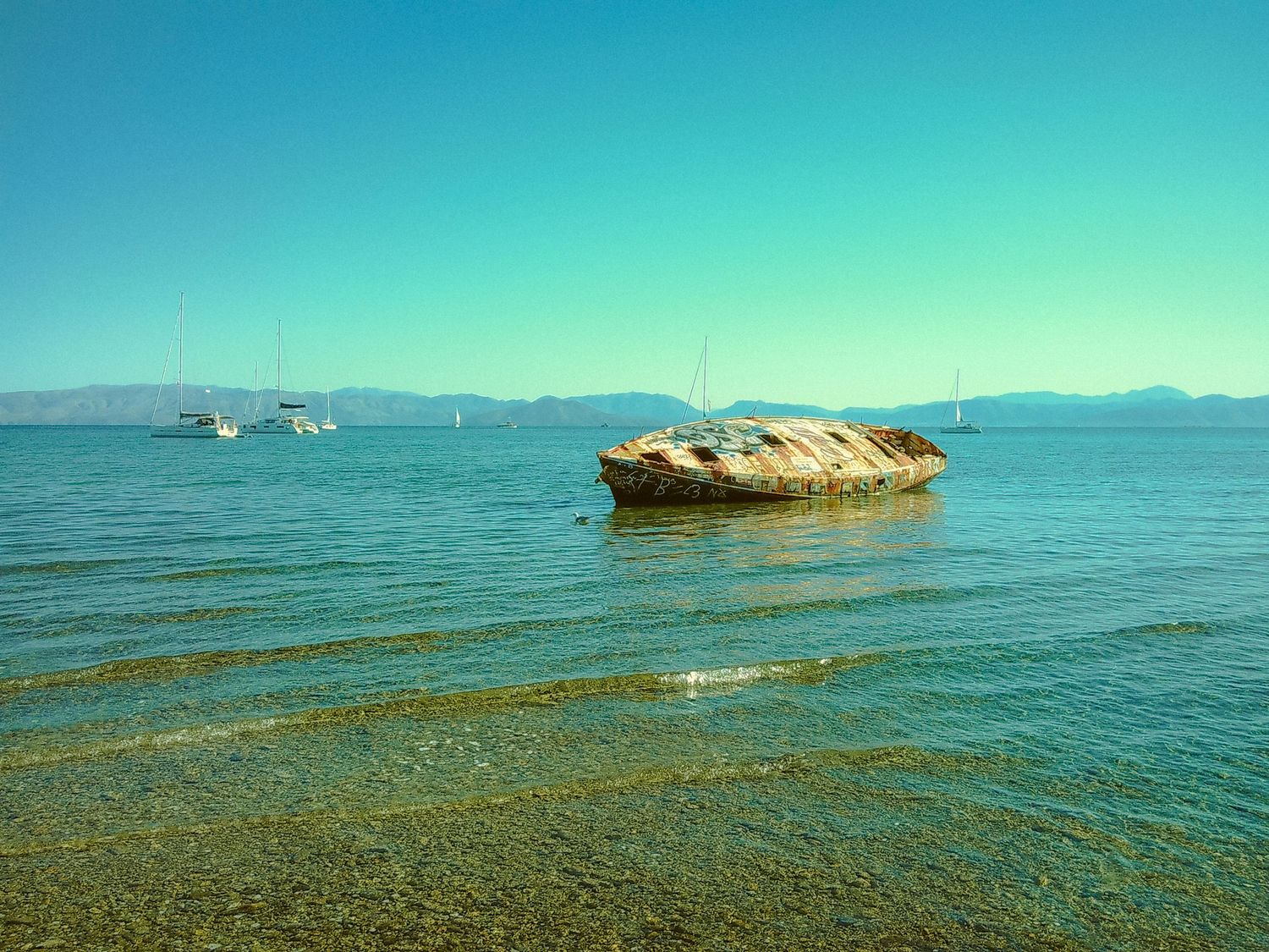Panoramic seascape with calm blue waters stretching to distant mountains.