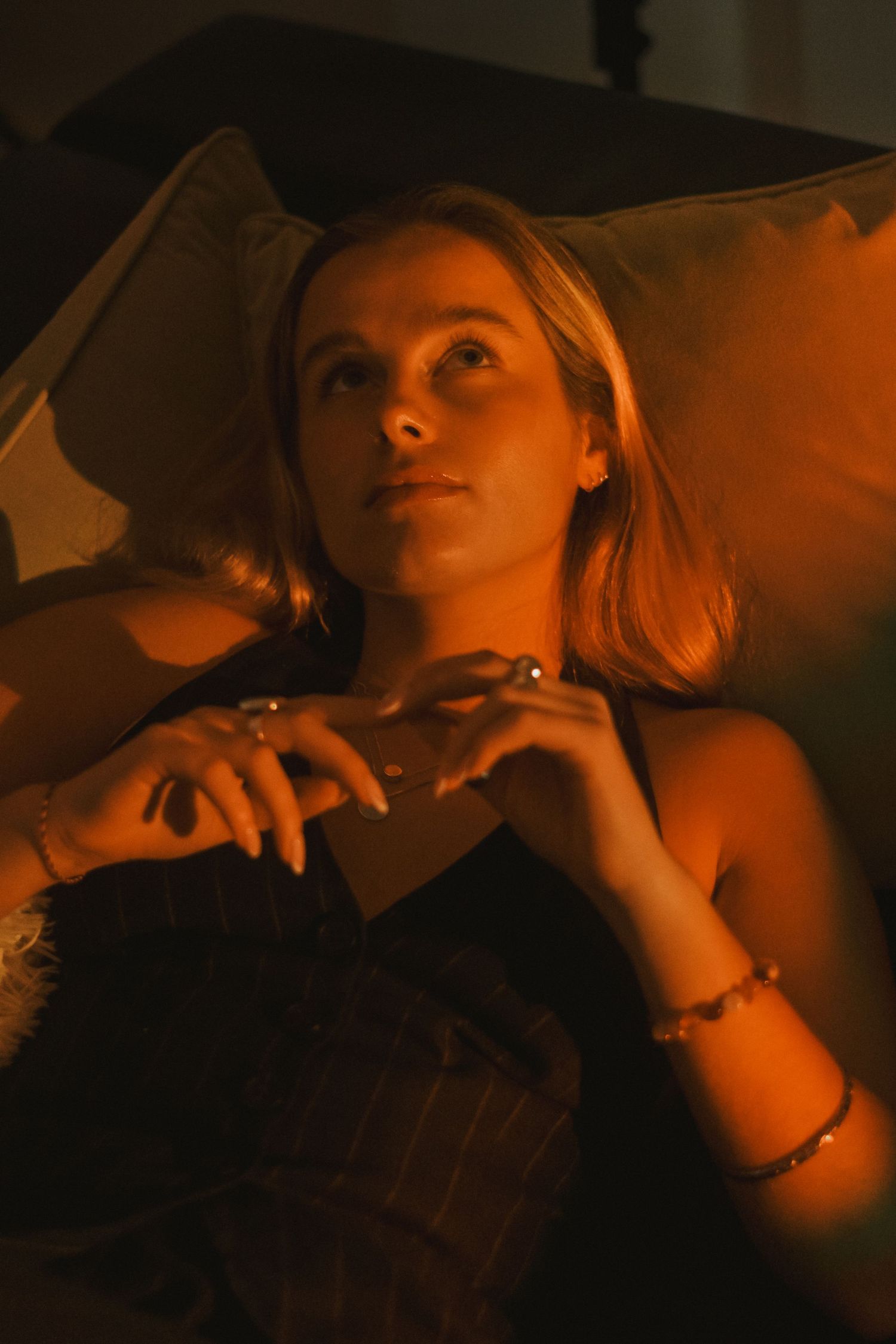 Cinematic shot of person lying on couch with dramatic lighting and jewelry.