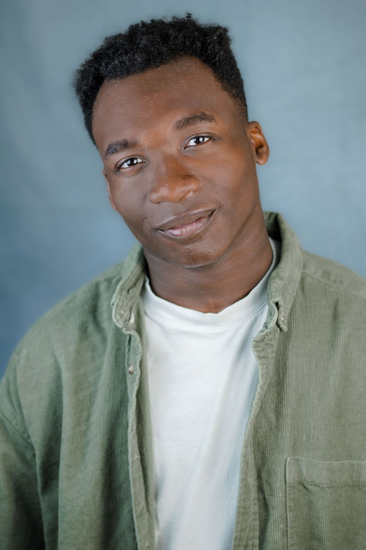 Casual portrait series wearing sage green button-up shirt over white t-shirt.