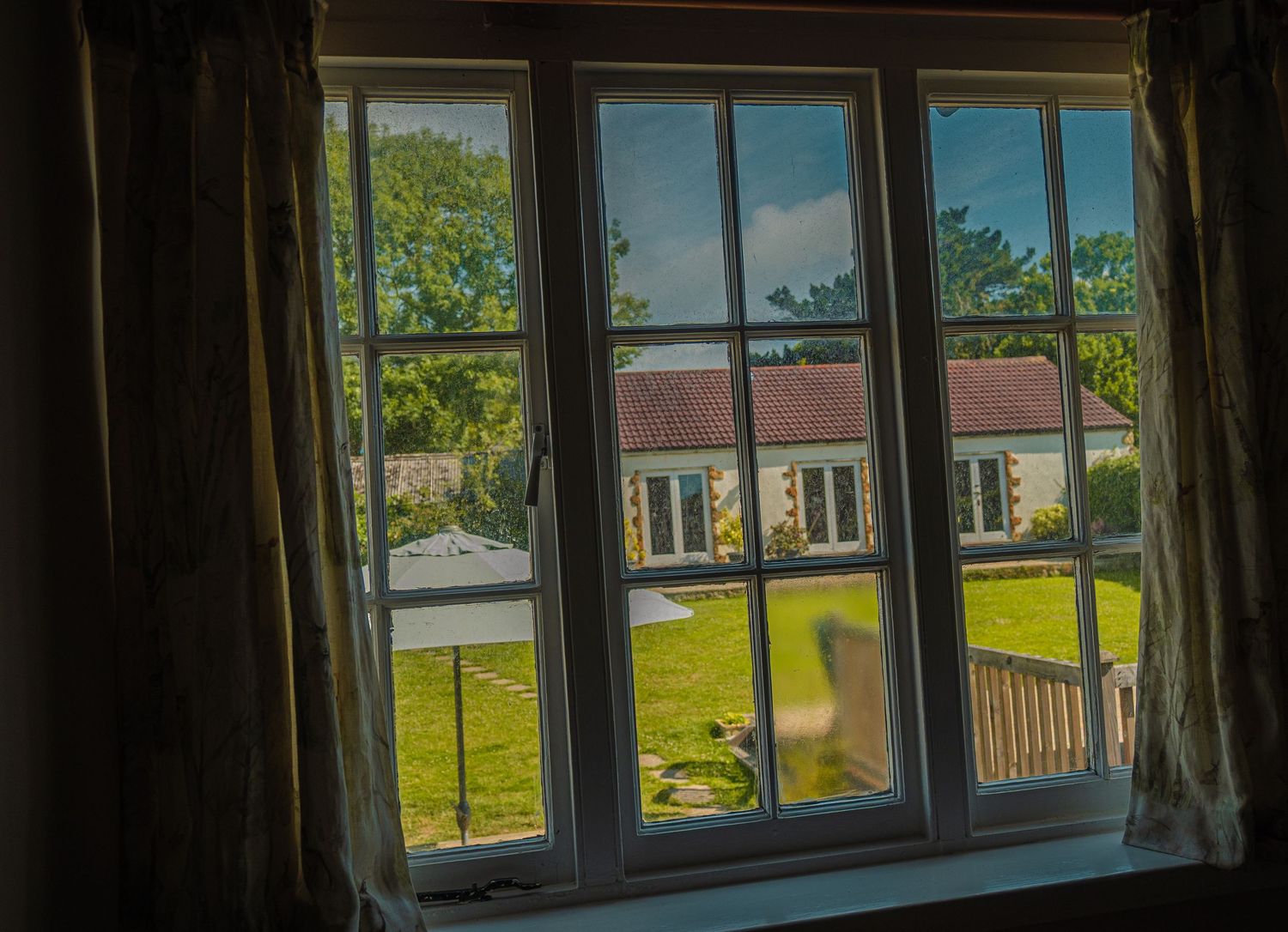 Panoramic view through multiple windows looking out onto a sunny green landscape.