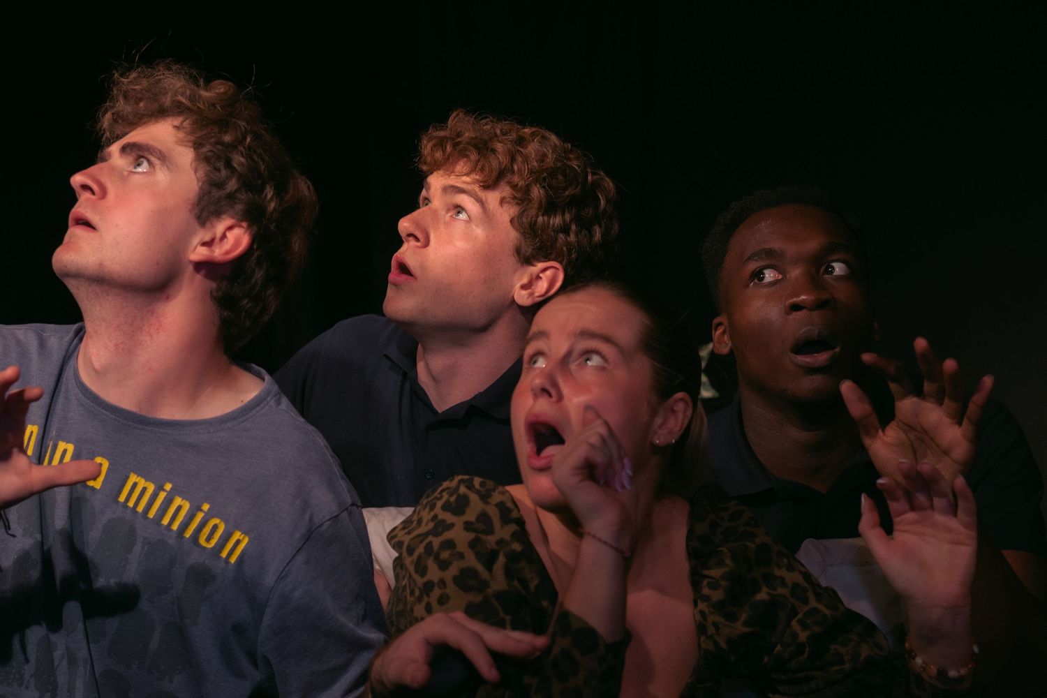 People displaying animated expressions while watching something in a dark room.