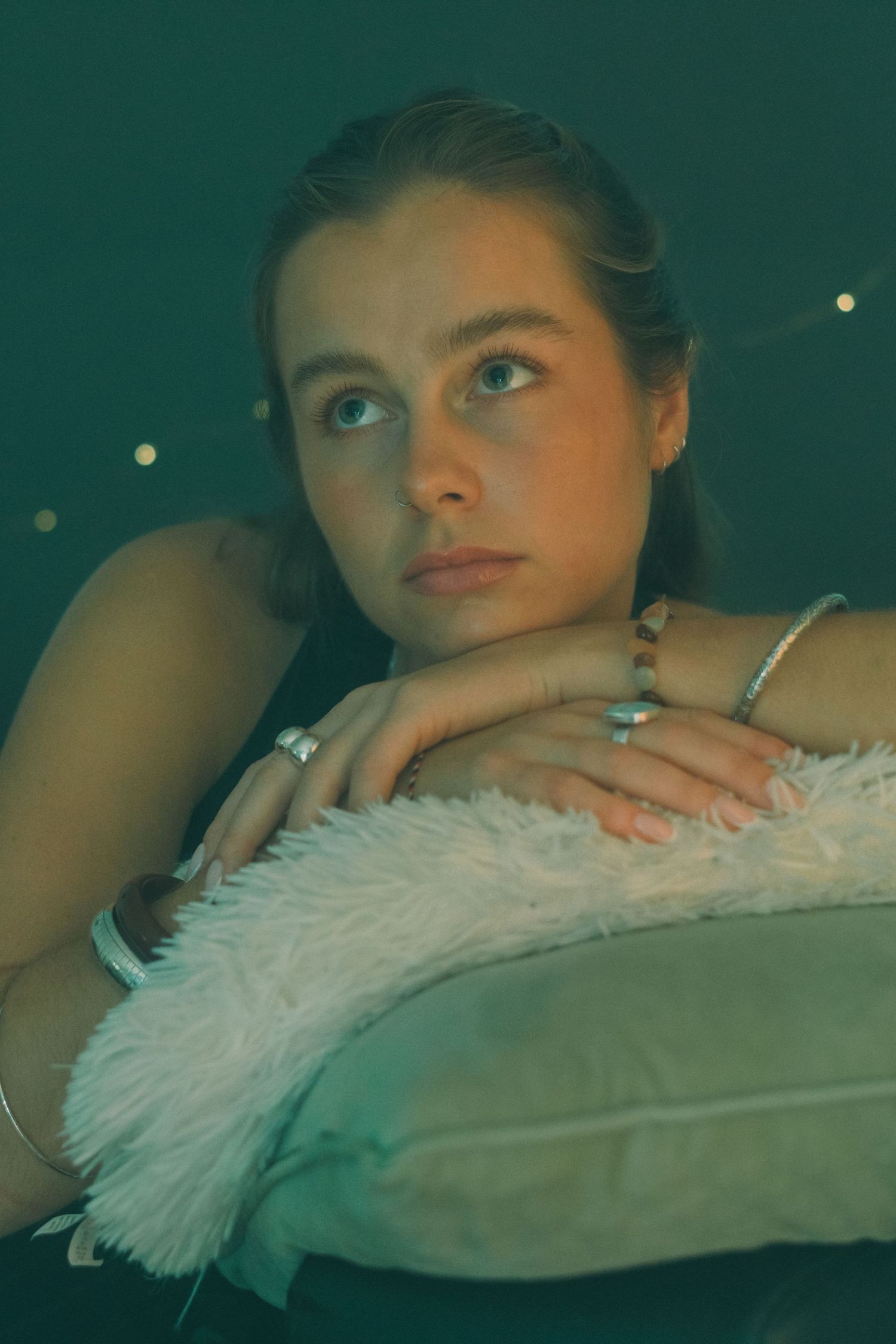 A dreamy portrait featuring soft white feathers and a moody green-tinted backdrop.