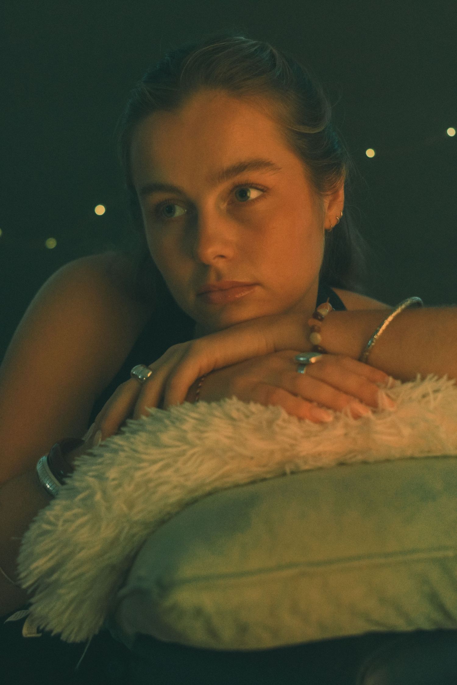 Dramatic low-light portrait with textured pillow and ambient lighting.