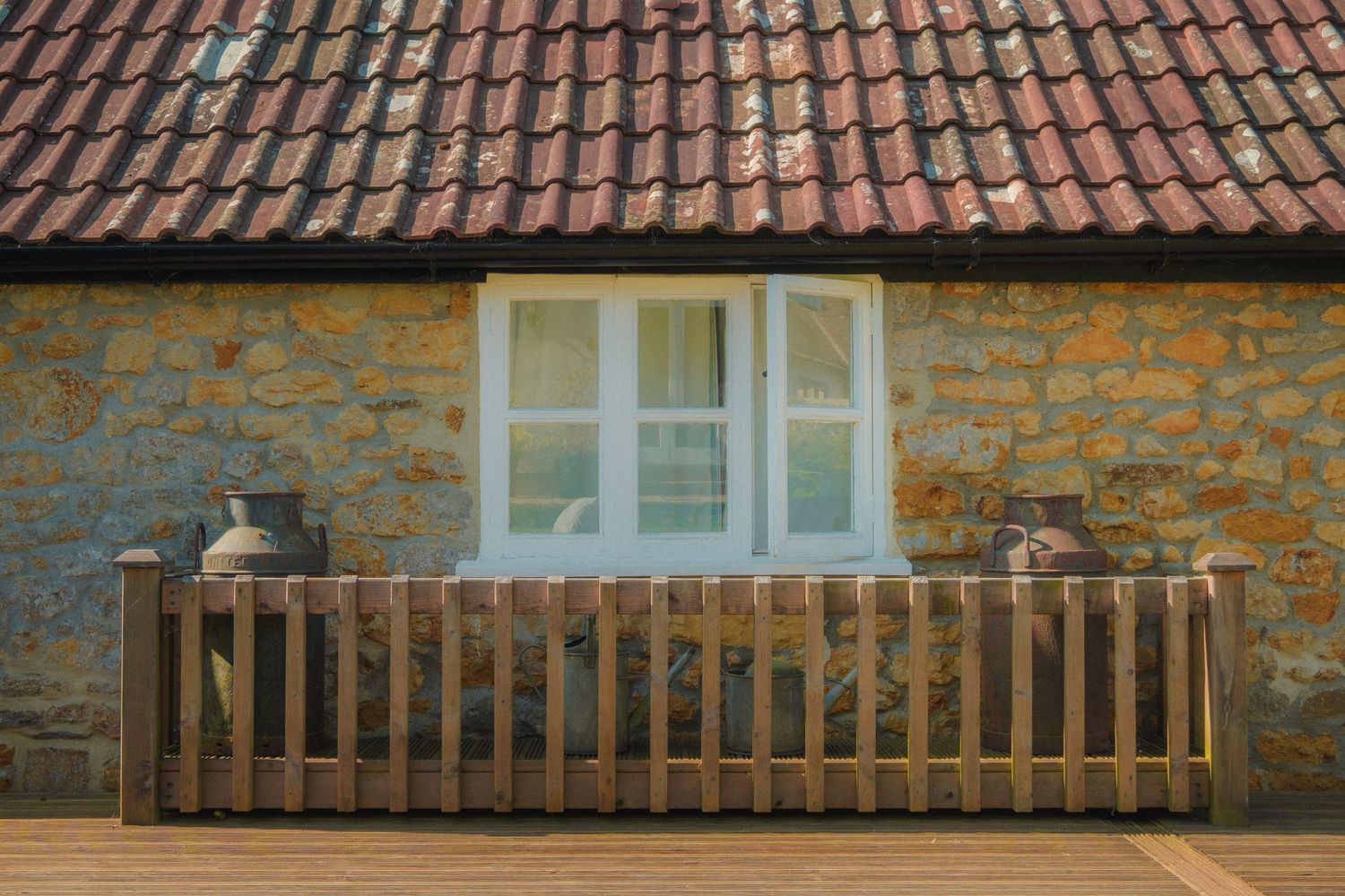 Traditional terracotta tiled roof with stone walls and wooden railing detail.