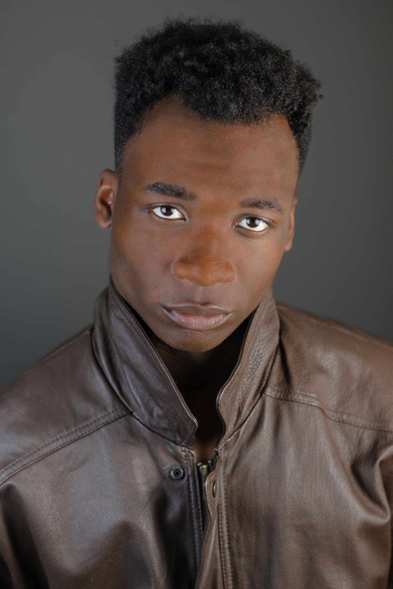 Studio portrait series with dramatic lighting and brown leather jacket.
