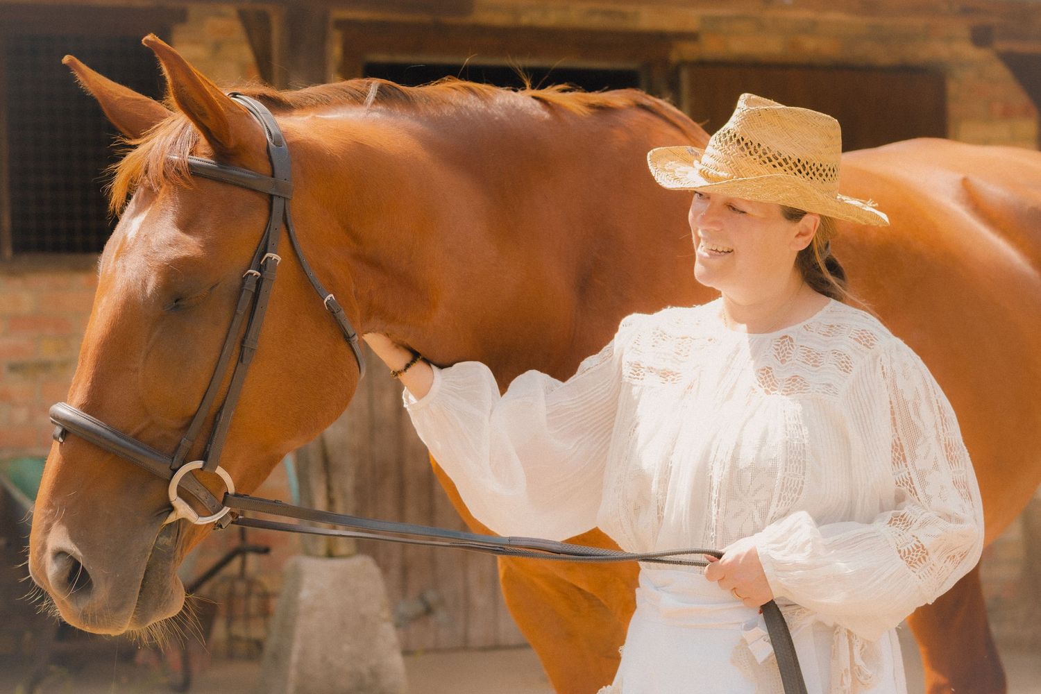 A tender moment shared between a chestnut horse and someone wearing a flowing white dress.