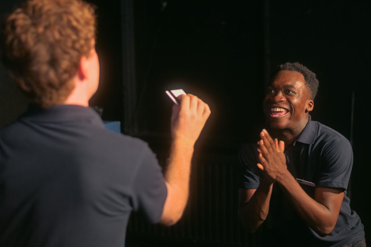 Several people laughing and gesturing enthusiastically in a dark room.