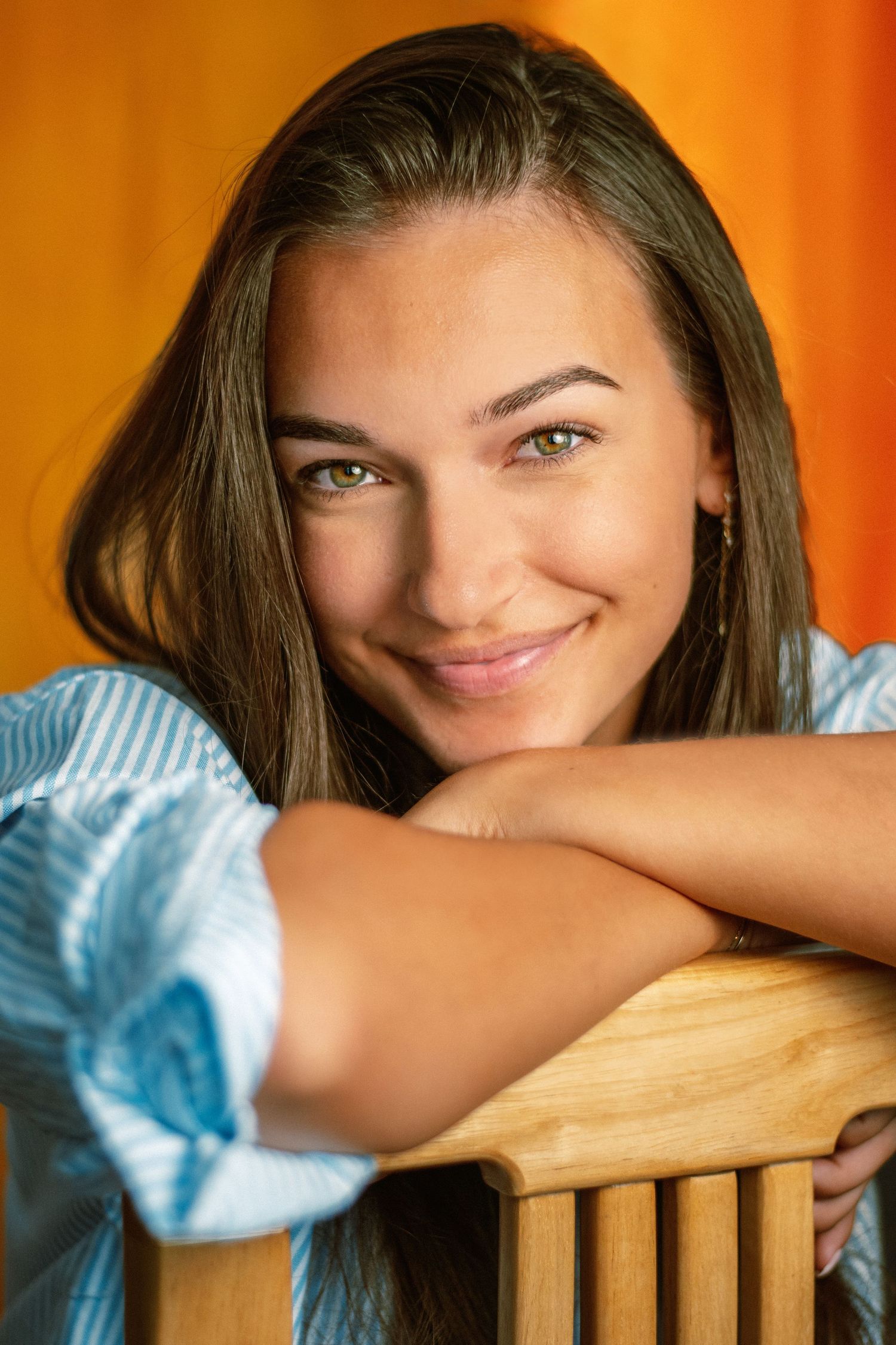 Studio portrait series with warm orange background showing playful expressions.