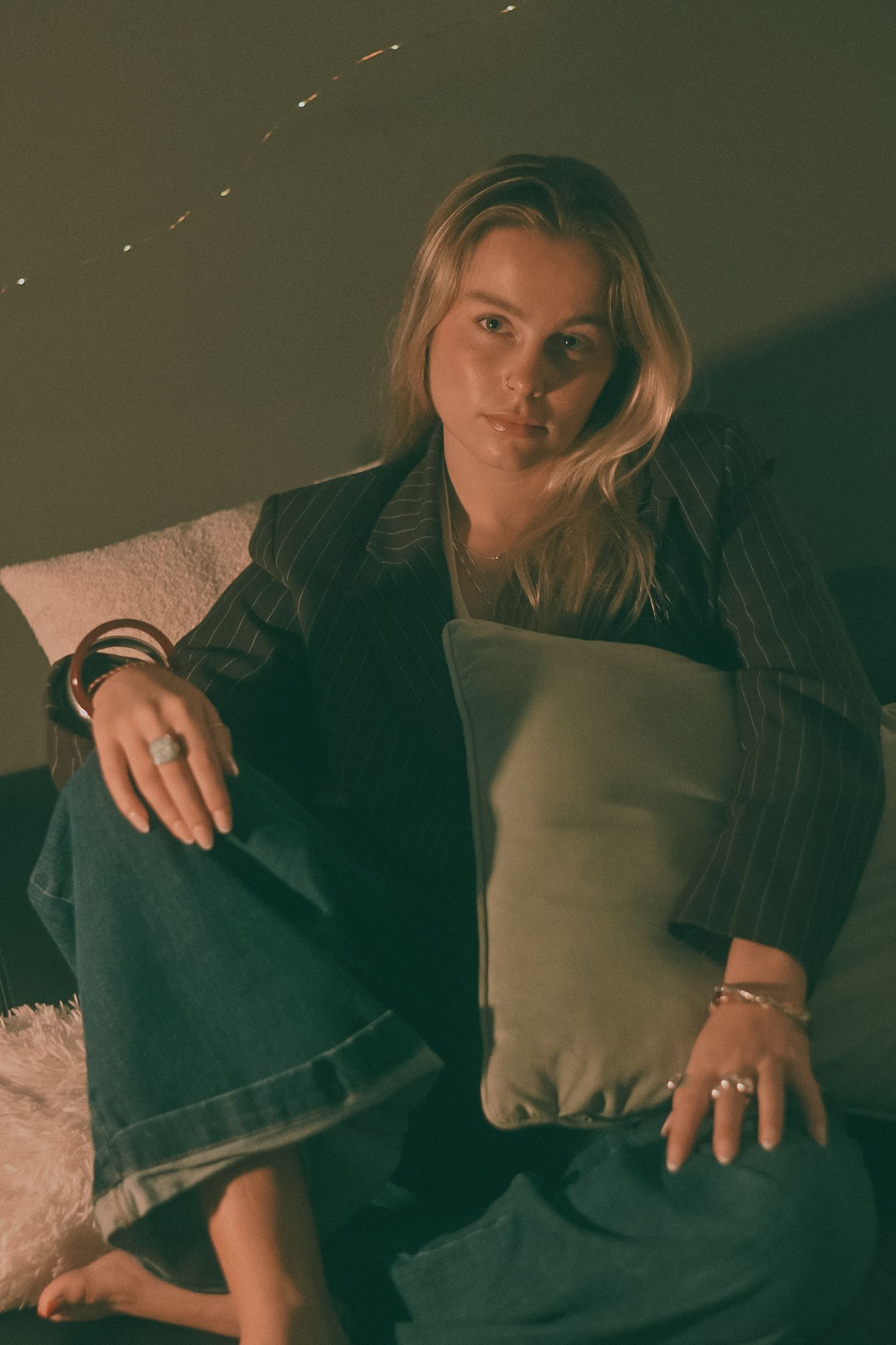 Atmospheric shots of someone lounging on furniture in dark formal wear.