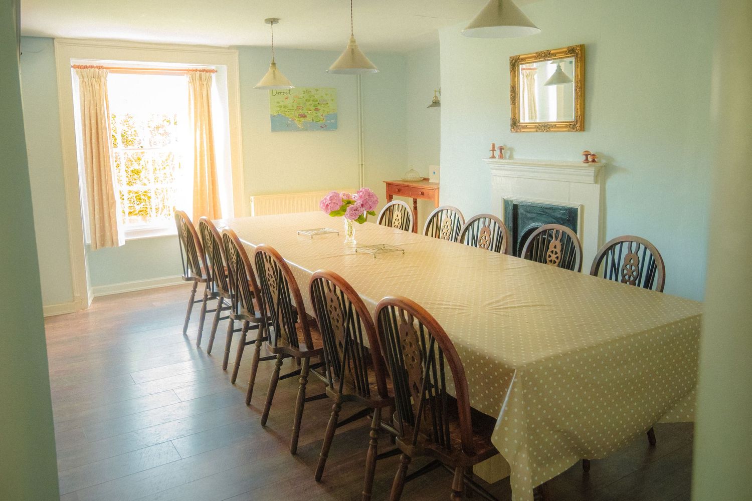 Large dining room with wooden Windsor chairs and white tablecloths arranged in long rows.