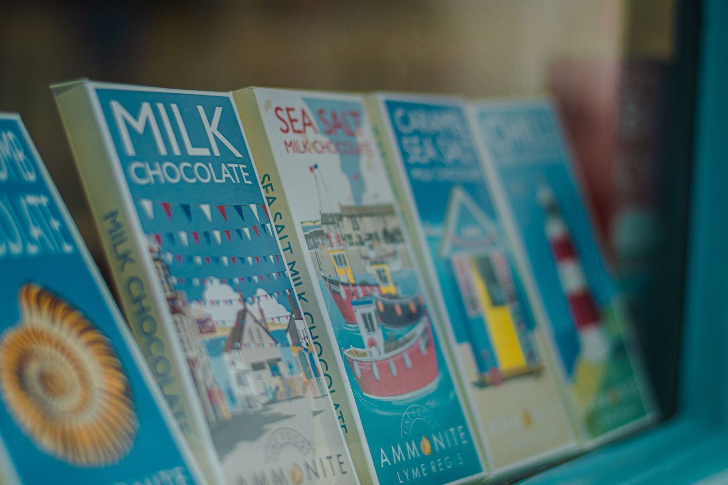 Collection of vintage milk chocolate and candy tins displayed on blue shelving.
