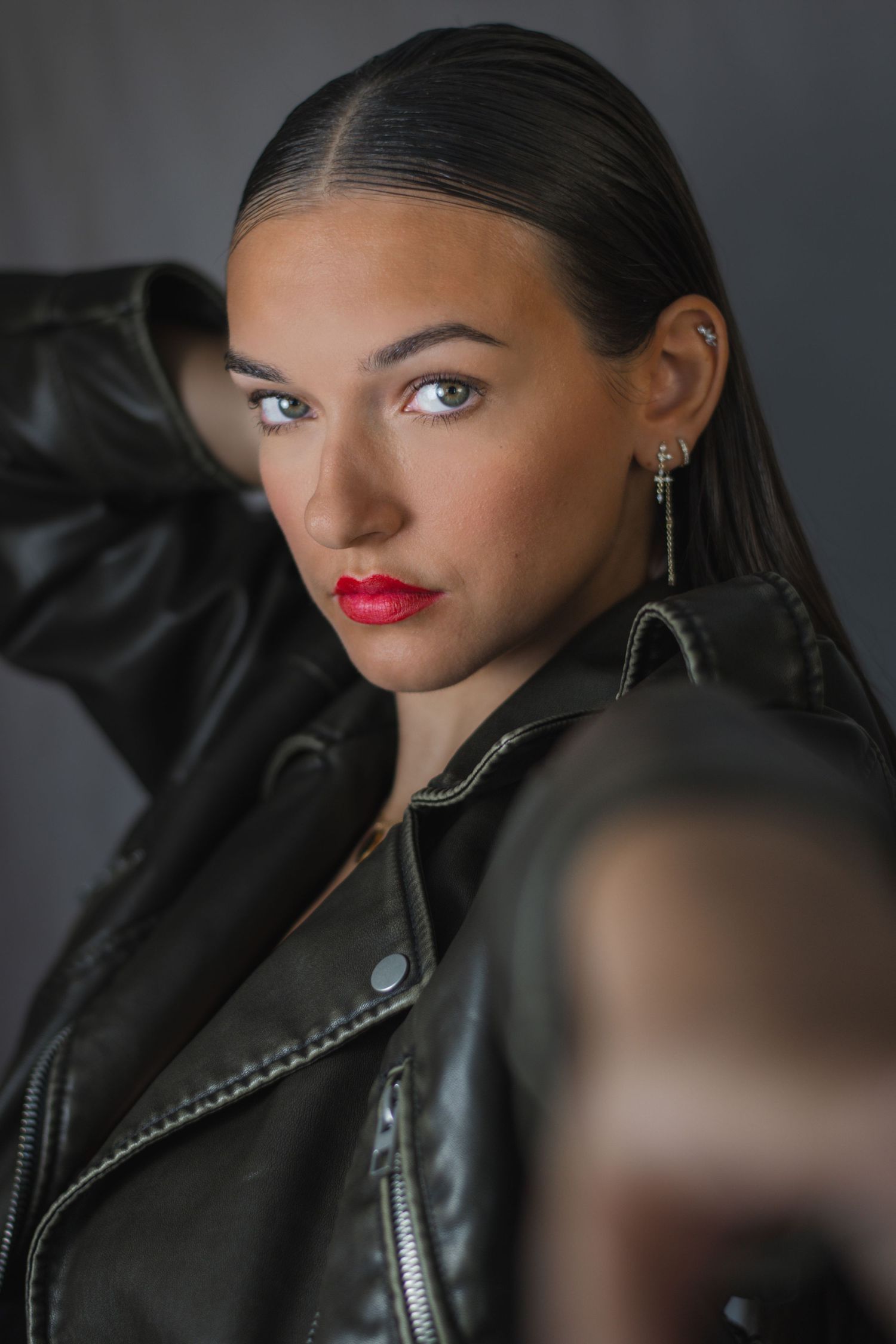Side profile shot in leather jacket showing dramatic lighting and makeup.