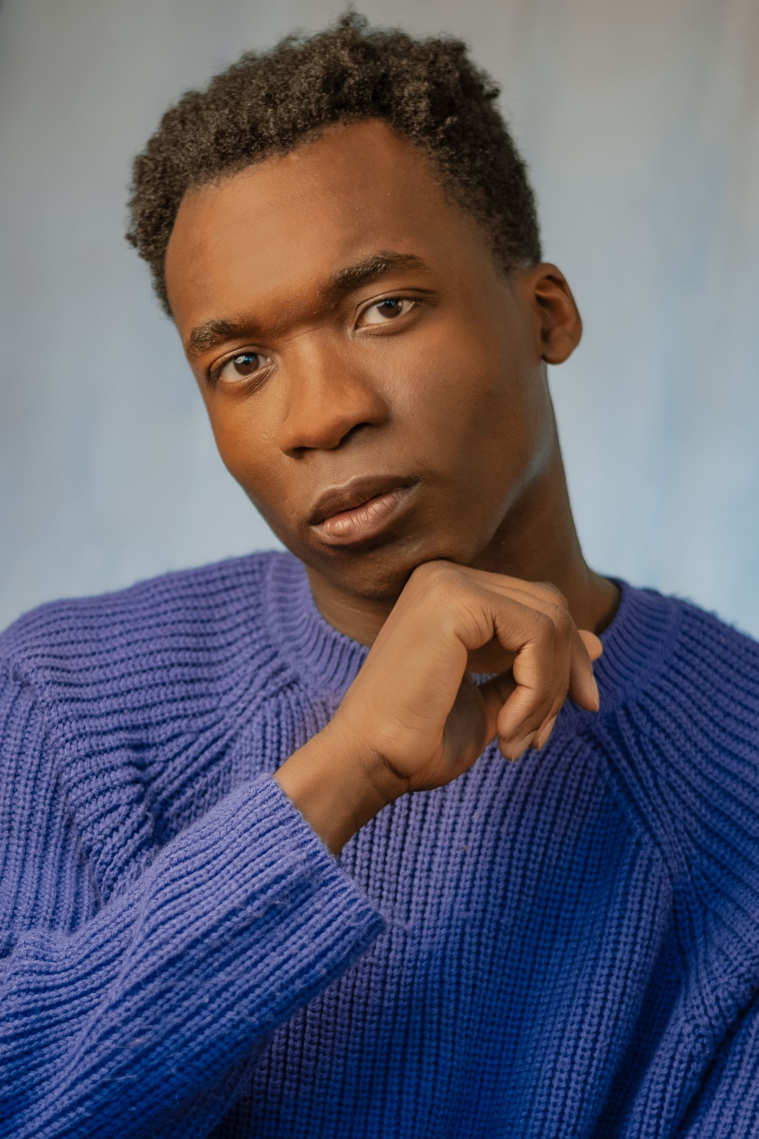 Expressive portrait series in a cozy blue knit sweater against light background.
