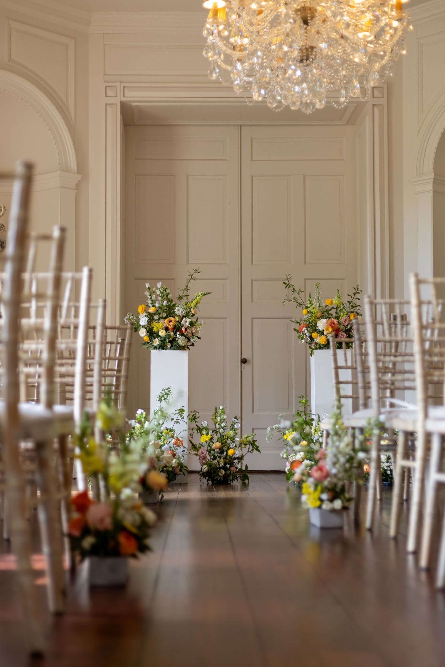 Elegant reception hall with crystal chandelier and white chiavari chairs.