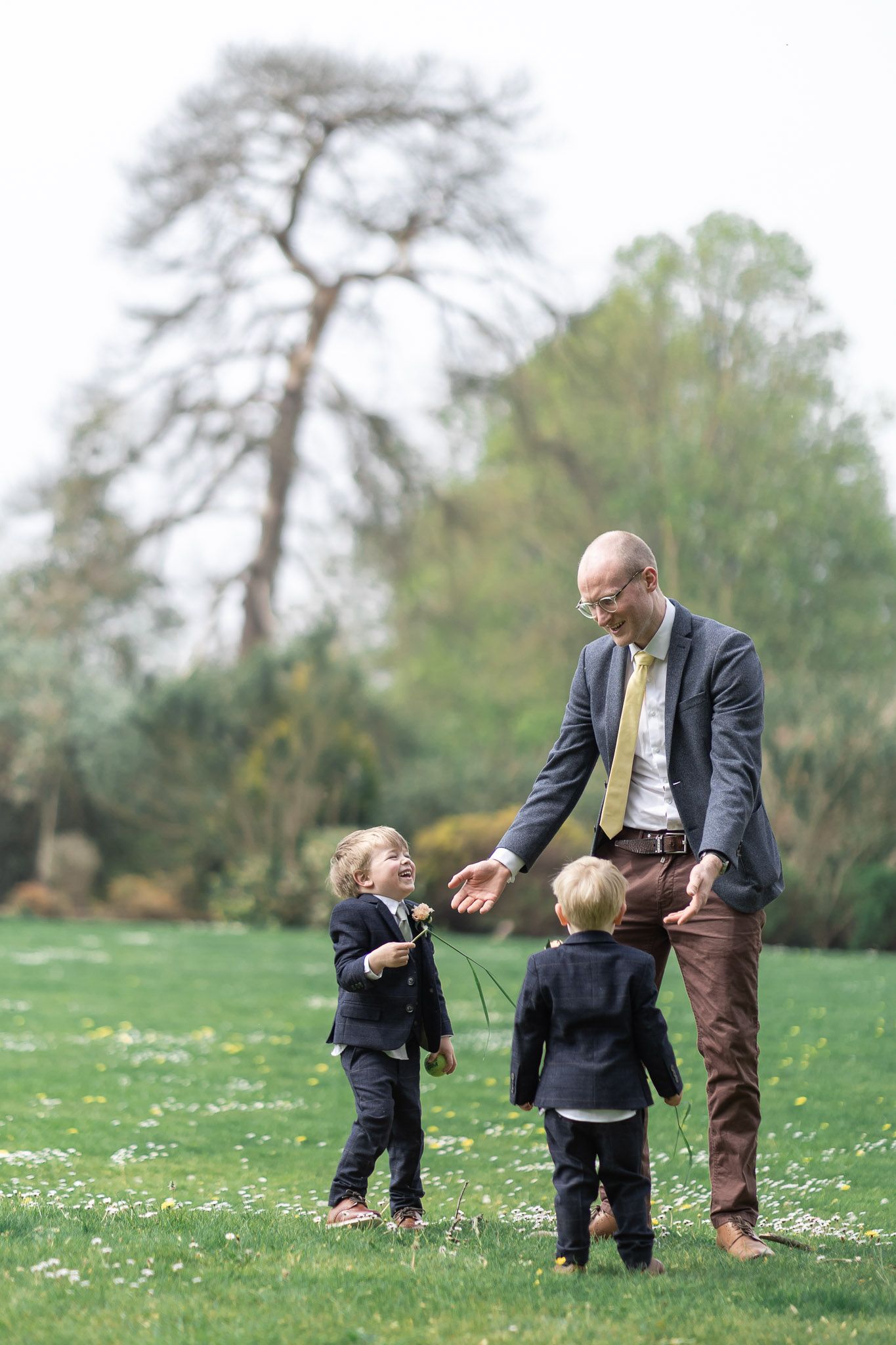 Three figures running and playing in a spring meadow dotted with daisies.