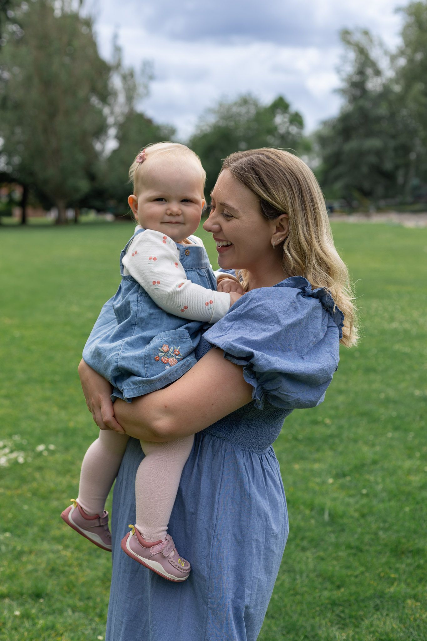 A joyful outdoor family moment captured in a park with matching blue outfits.