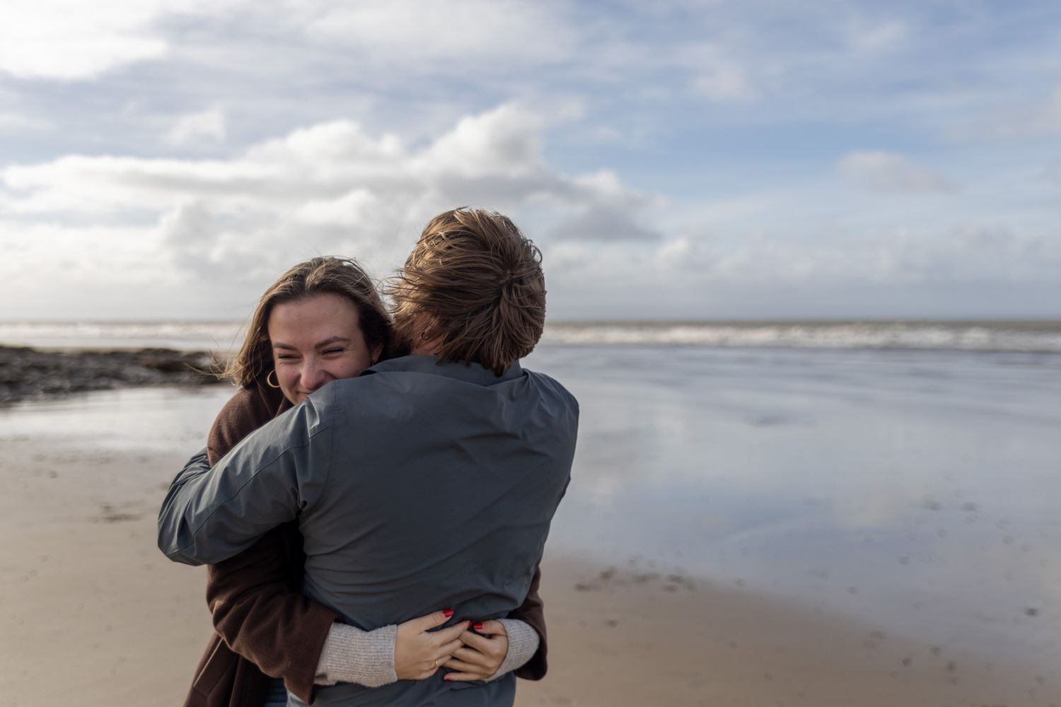 A tender moment between two people hugging on an empty beach.