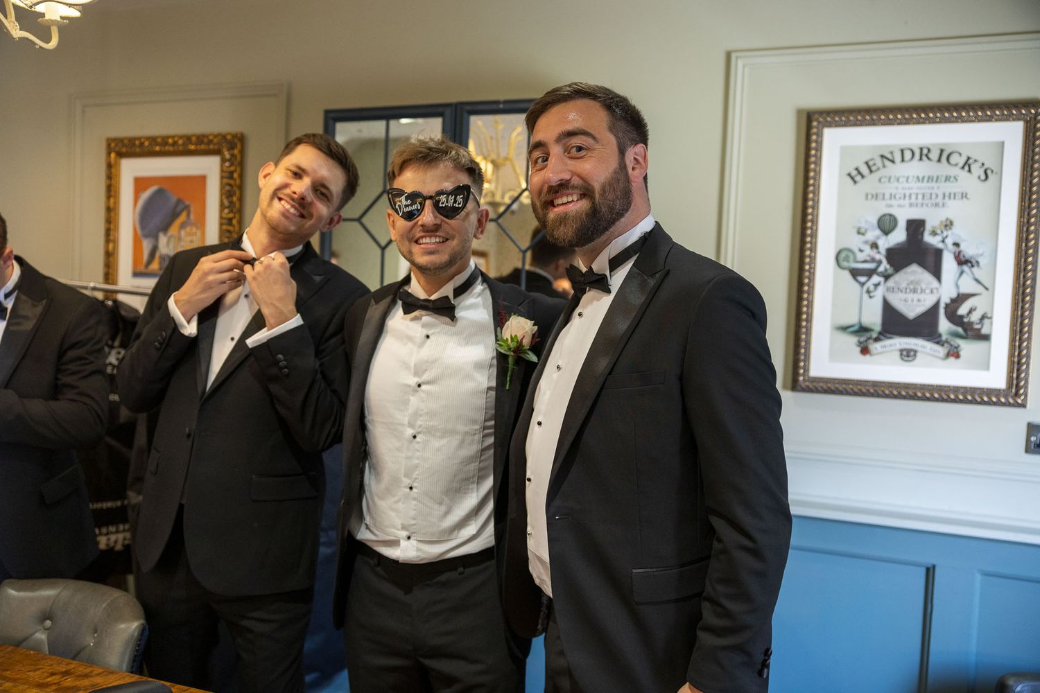 Groom and groomsmen formal attire with bow ties and tuxedos smile together while getting ready for the wedding.