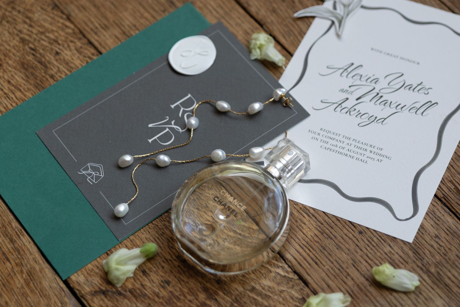 Wedding invitation and cocktail on rustic wooden table with elegant details.