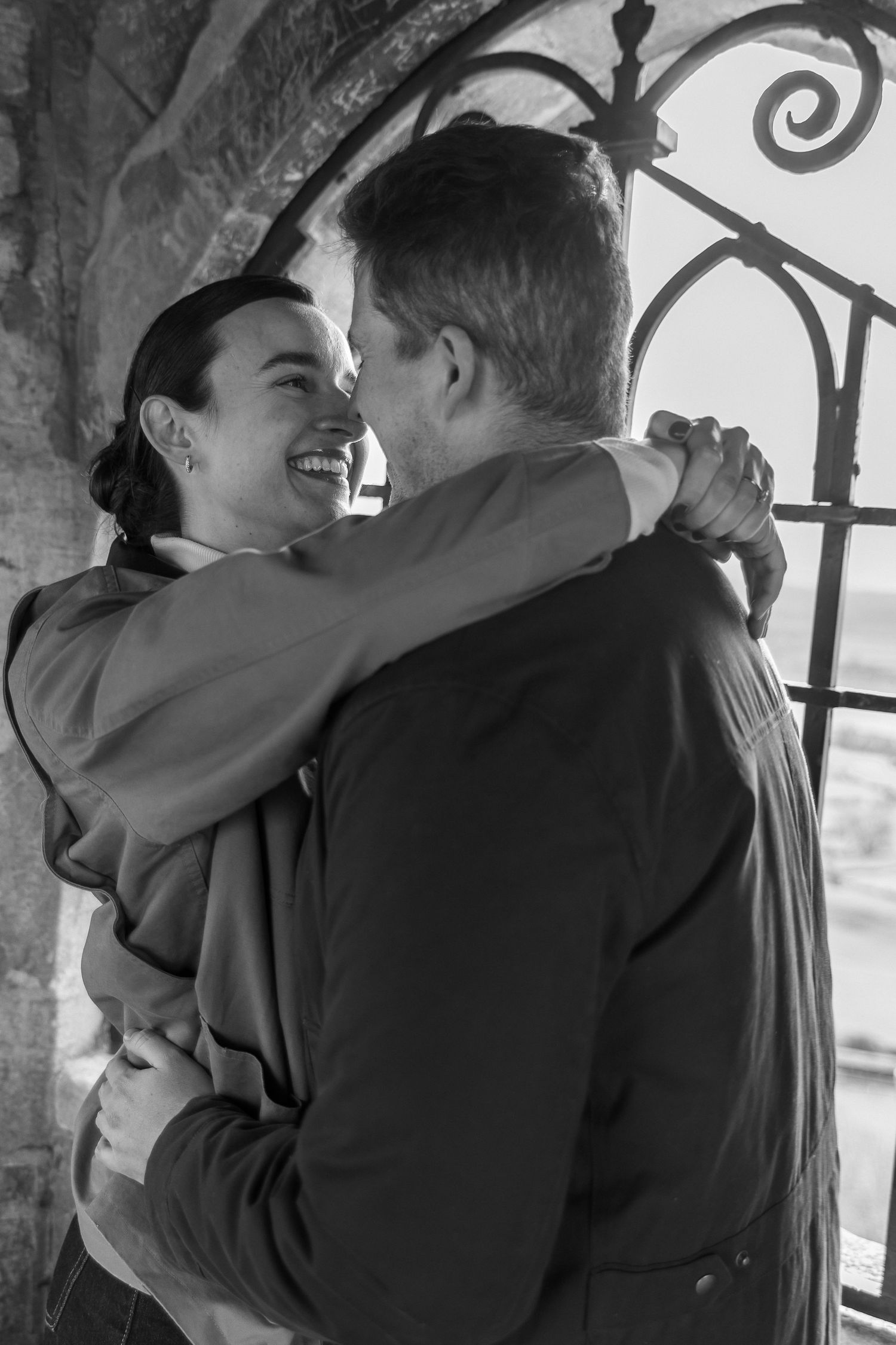 A romantic sequence of black and white photos showing a couple embracing and laughing together by a decorative window.